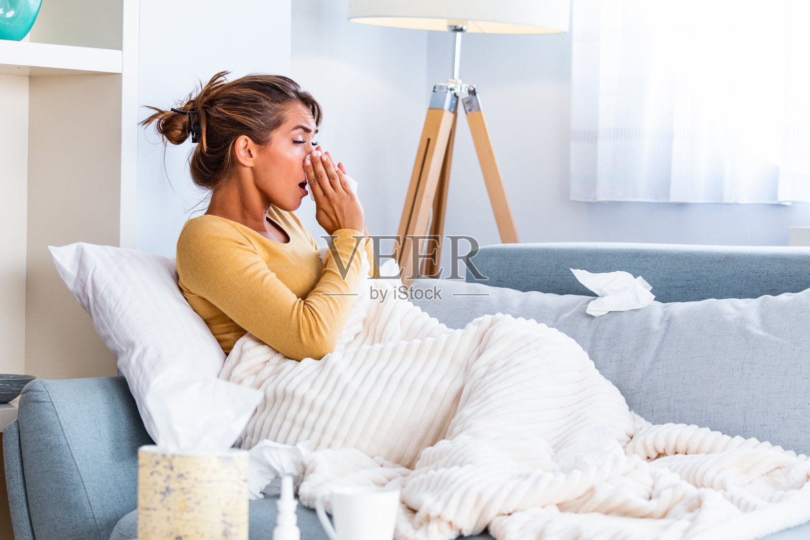 请病假在家。这位年轻女子得了感冒。咳嗽。美丽的年轻女子感冒或流感疾病的特写。不健康的女孩擤鼻子的肖像照片摄影图片