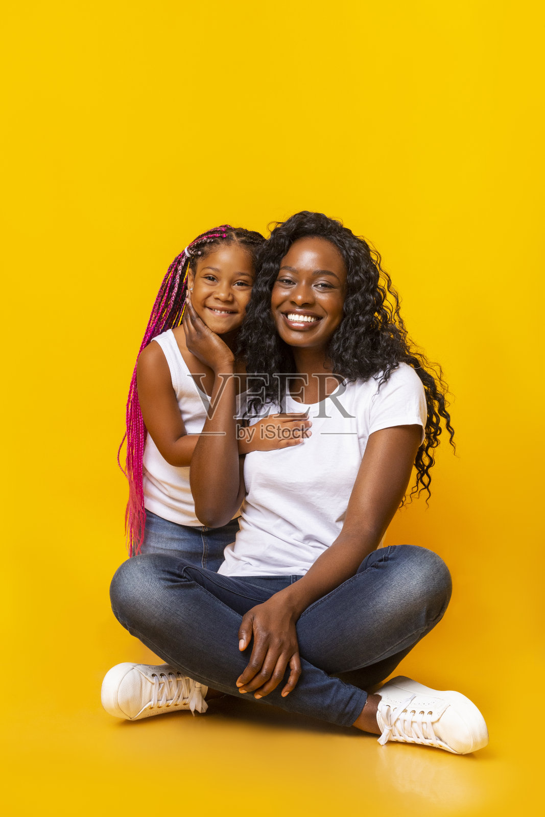 快乐的妈妈和她的小女儿拥抱在黄色的背景照片摄影图片