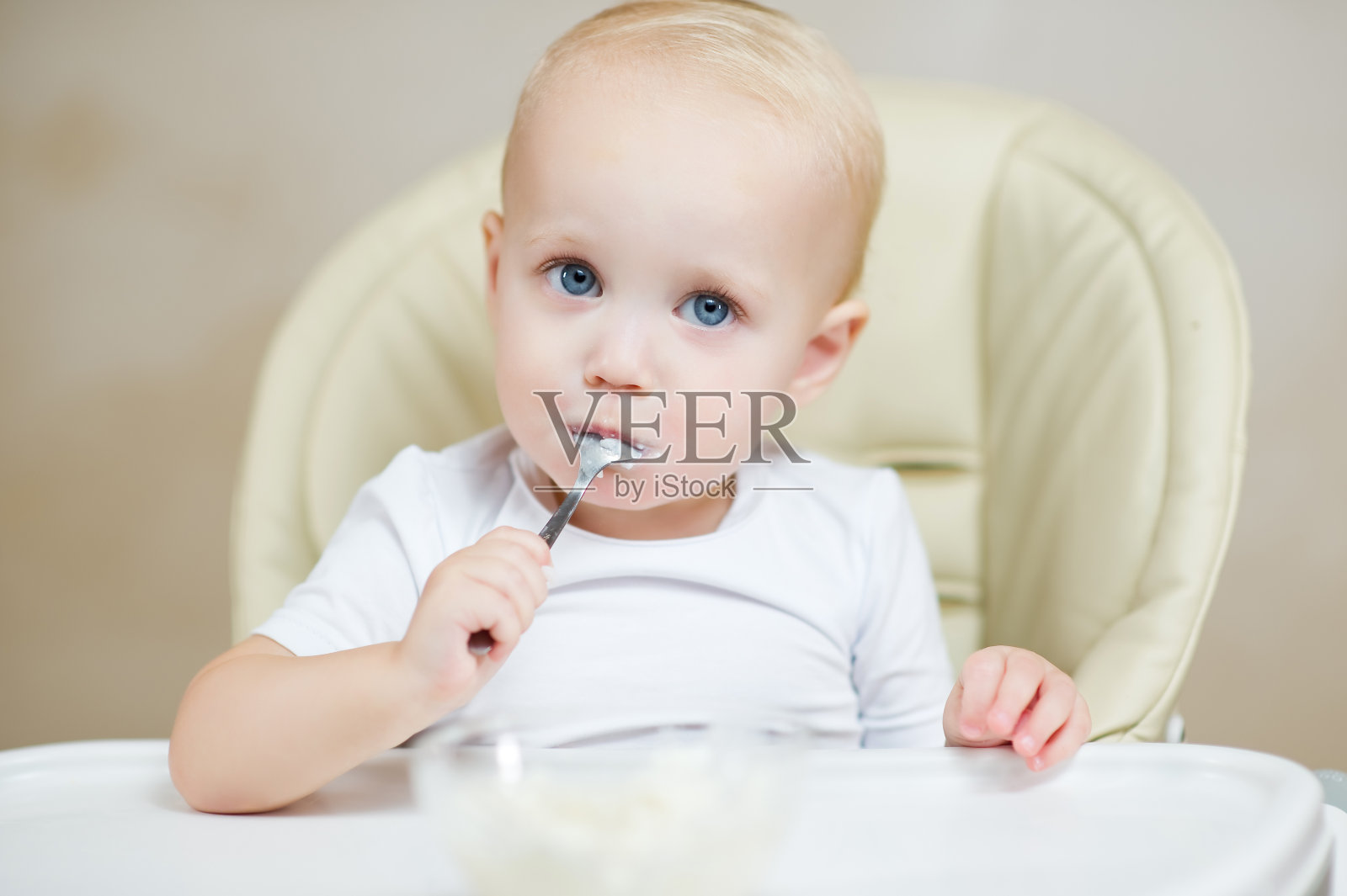 可爱的婴儿嘴里含着勺子看着镜头照片摄影图片
