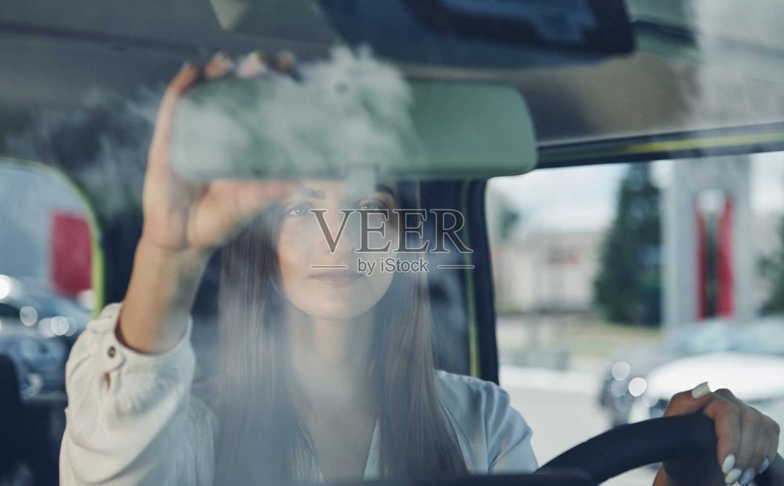 云在玻璃上的反射。在城市中驾驶现代新车的女人的正面视图照片摄影图片
