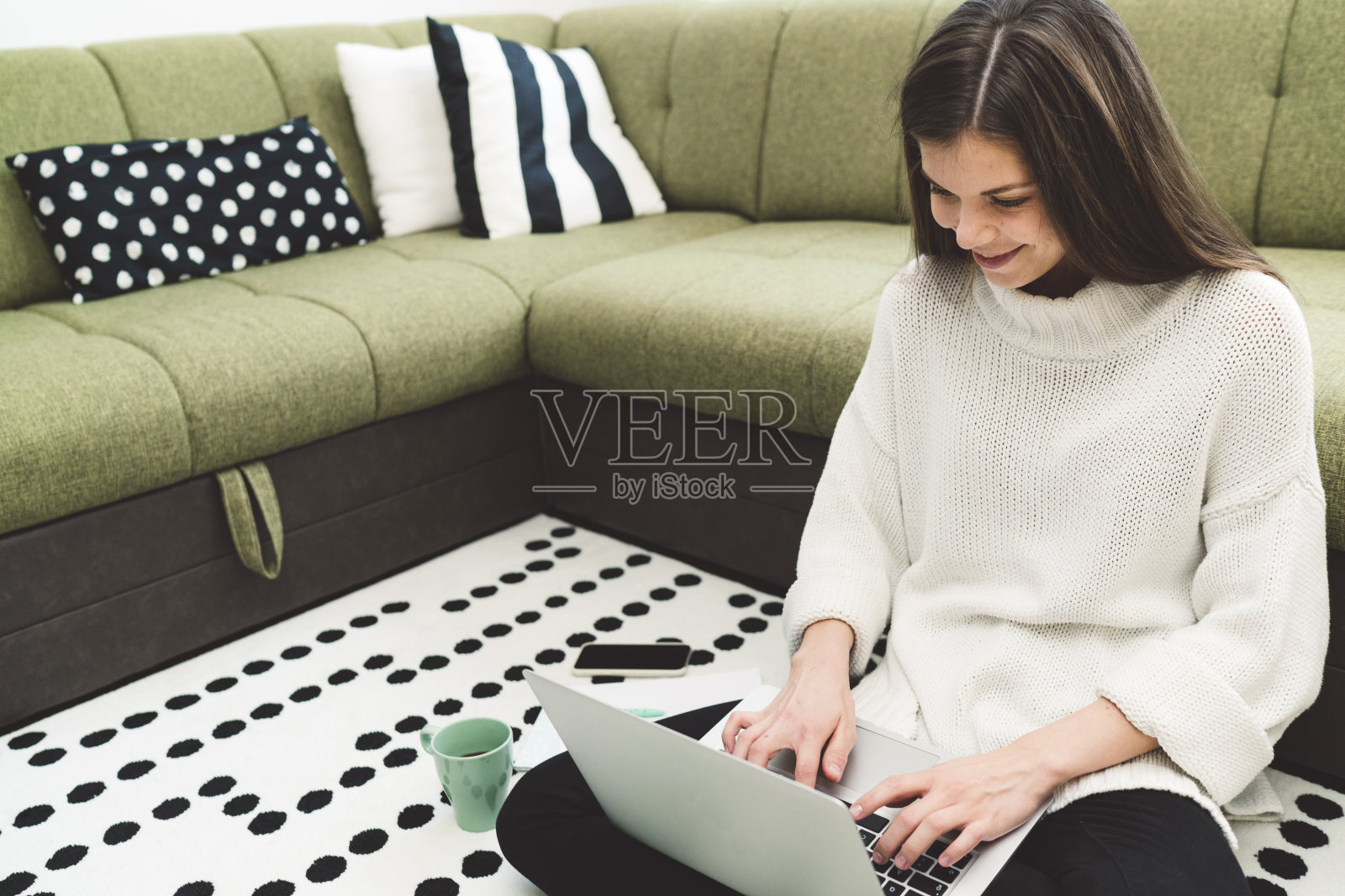 快乐的年轻女人坐在客厅的地毯上在家工作照片摄影图片