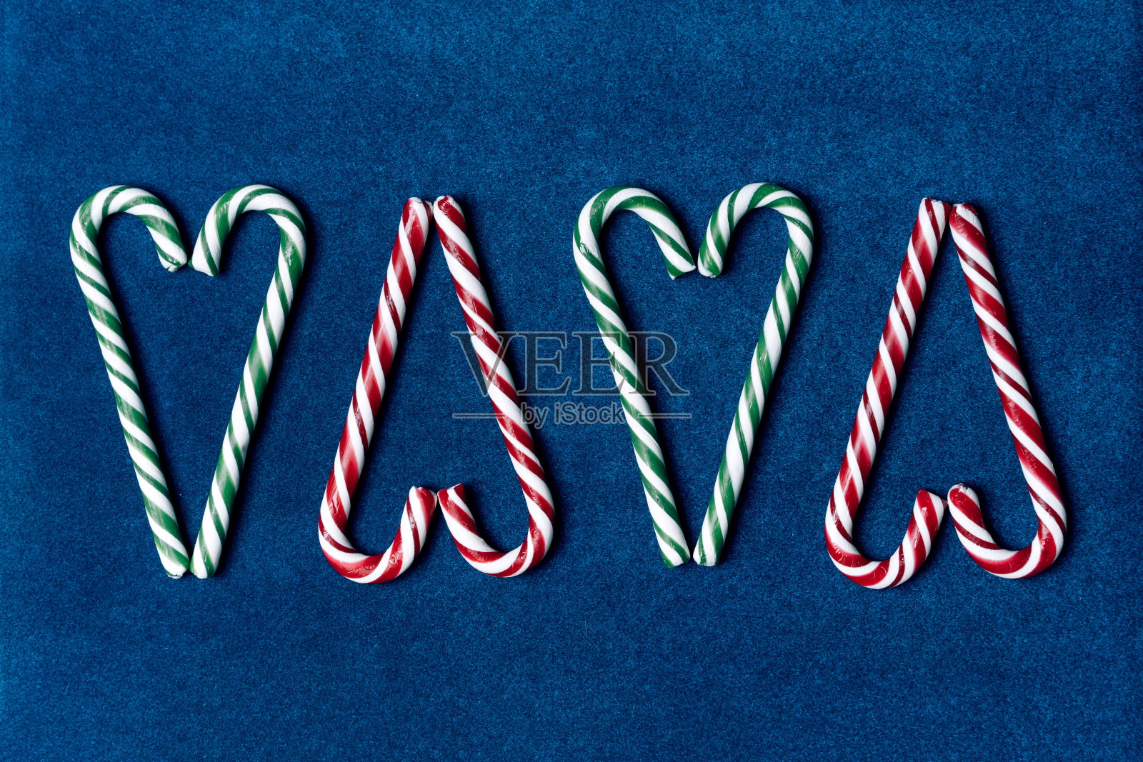 圣诞甜藤条纹绿色和红色折叠成心形在蓝色天鹅绒纸背景照片摄影图片