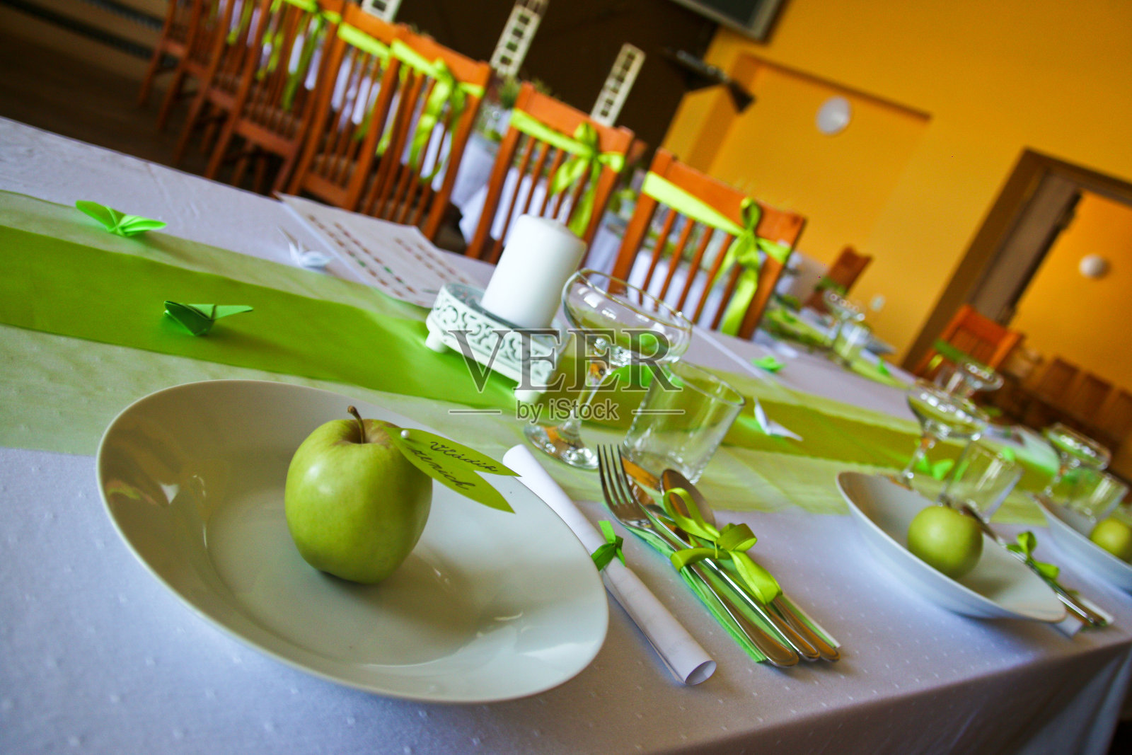 为婚礼准备的午餐桌子的详细图片。所有的配件都是绿色的。新鲜的青苹果在盘子里。照片摄影图片