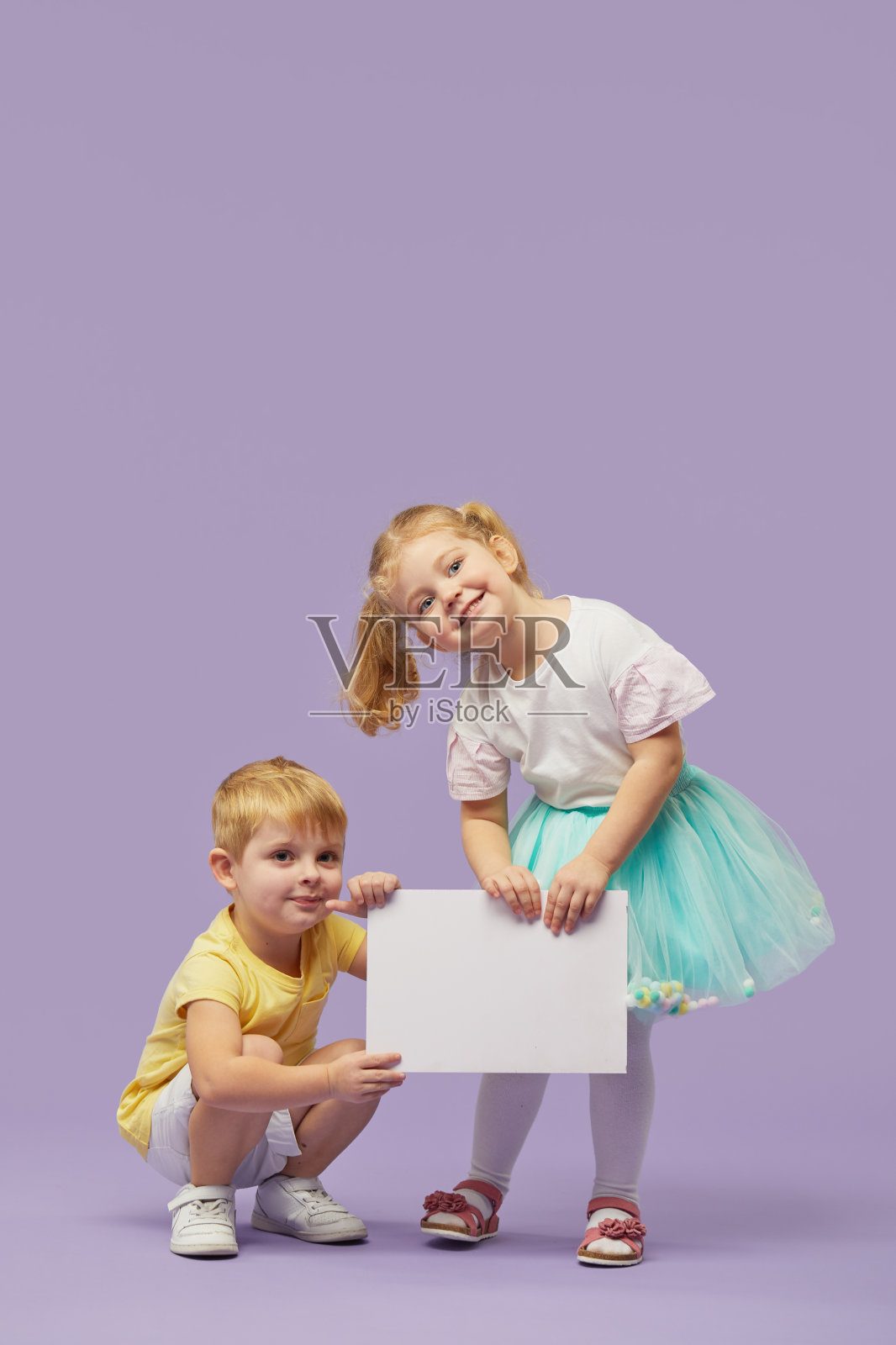两个小孩子在紫色的背景上举着白色的旗帜。有趣的脸。文本复制空间照片摄影图片