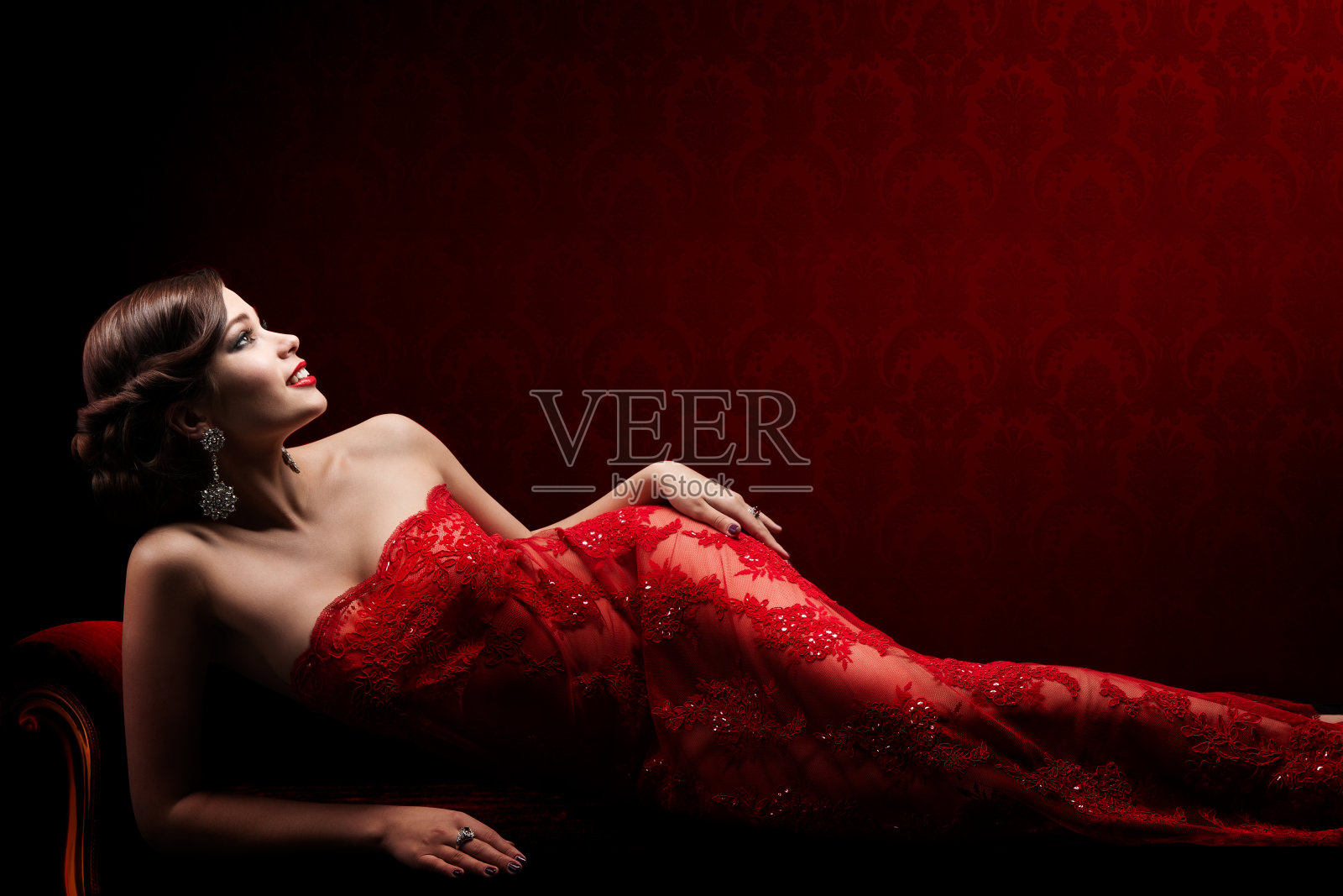 复古女性美在优雅的红色性感蕾丝连衣裙，美丽的时装模特躺照片摄影图片