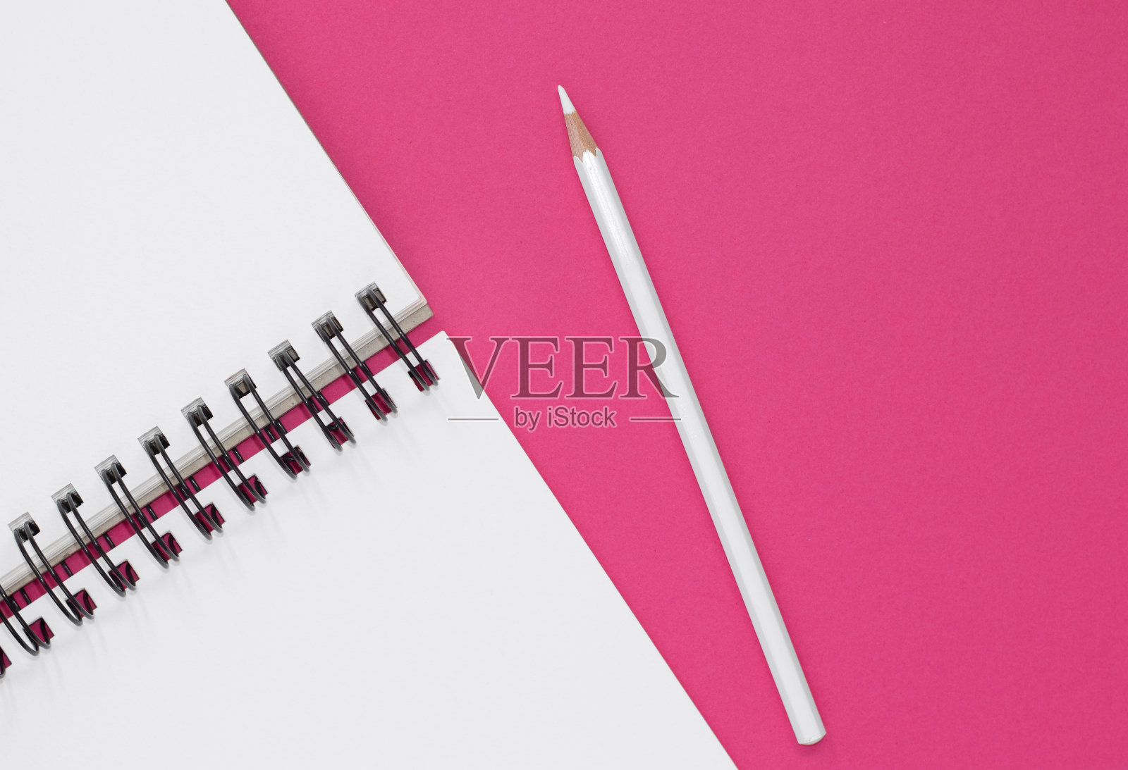 在粉红色背景上打开记事本和白色铅笔。照片摄影图片
