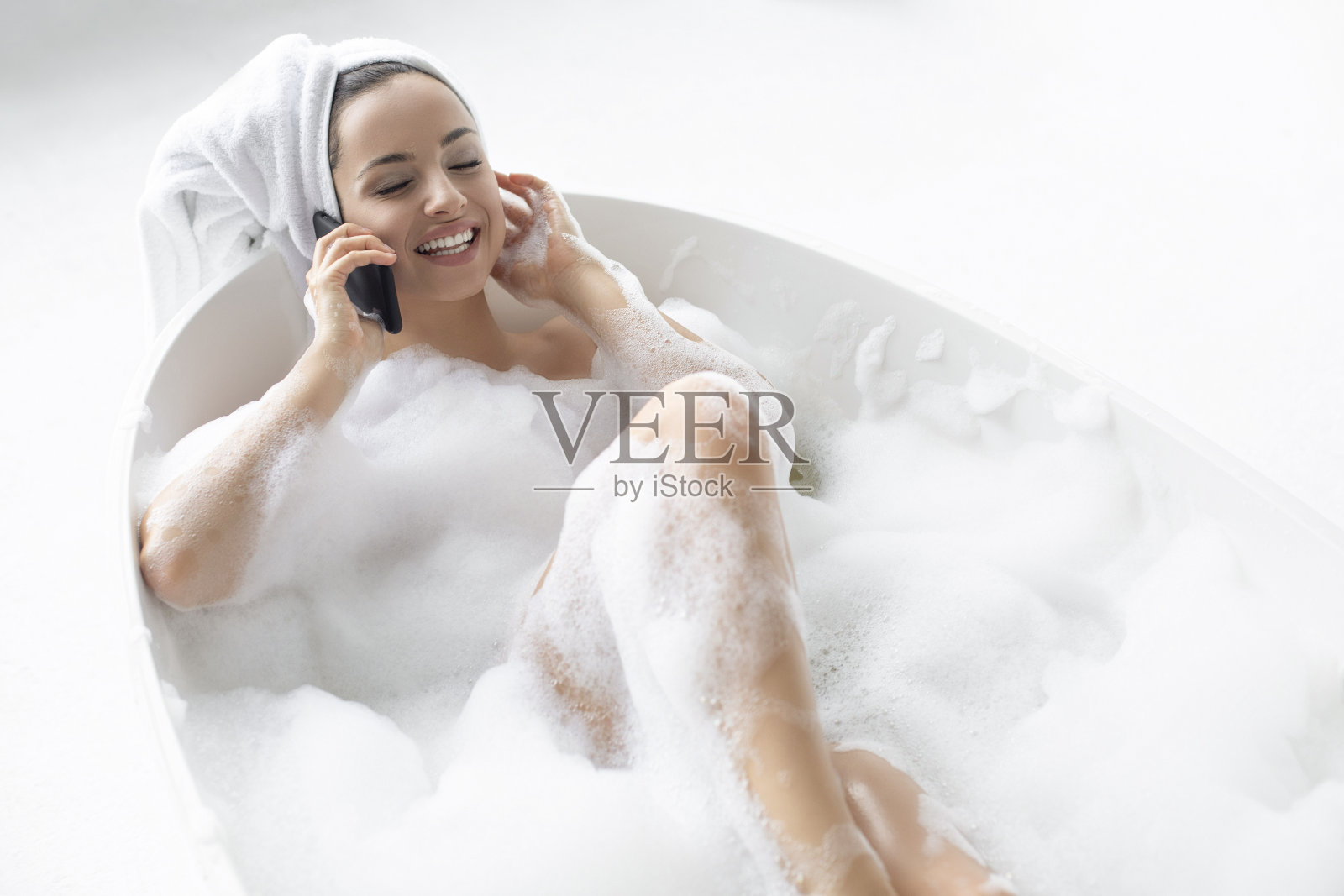 在浴缸里打电话的快乐女人照片摄影图片