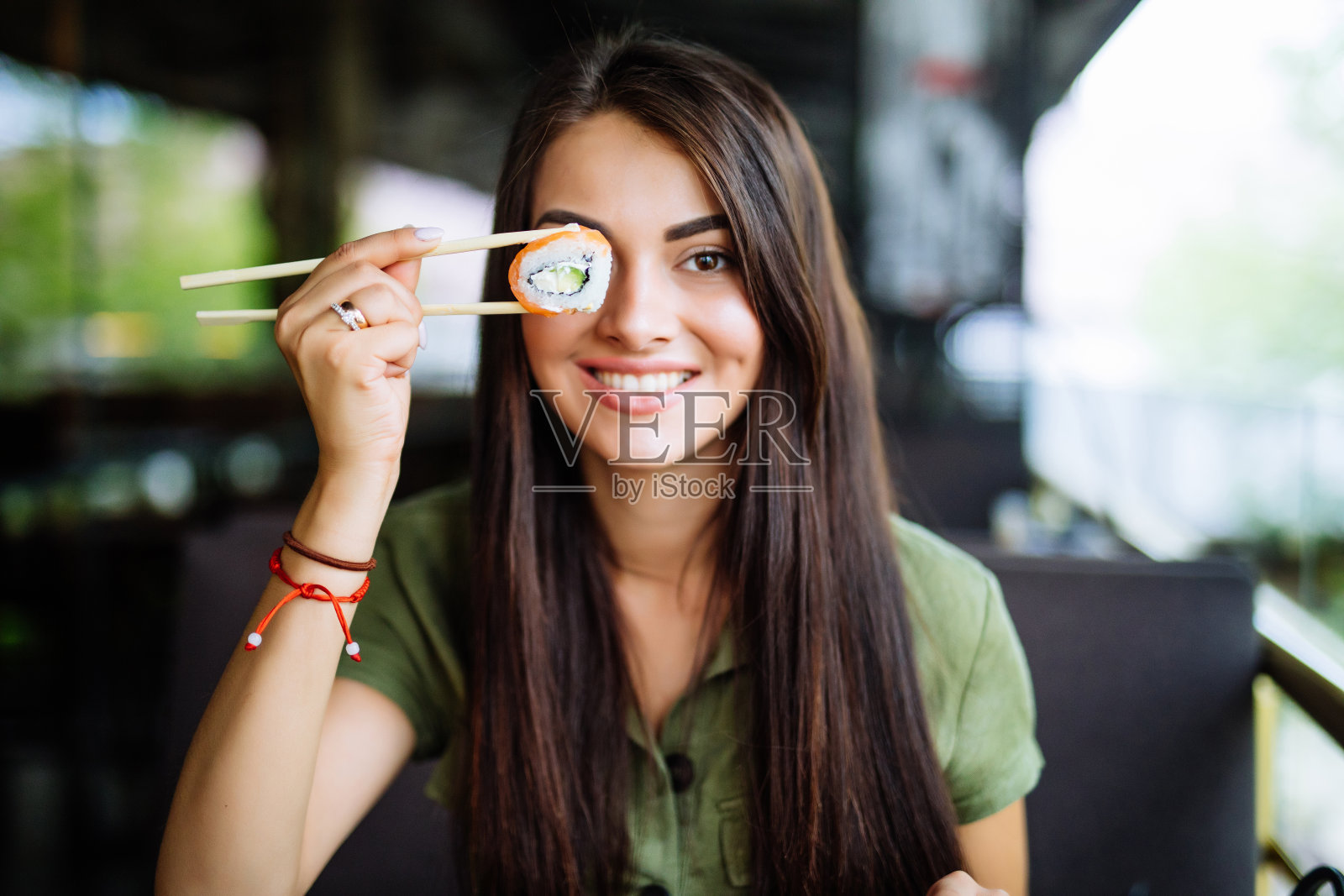 微笑的年轻女子拿着寿司在眼前与筷子在咖啡馆照片摄影图片