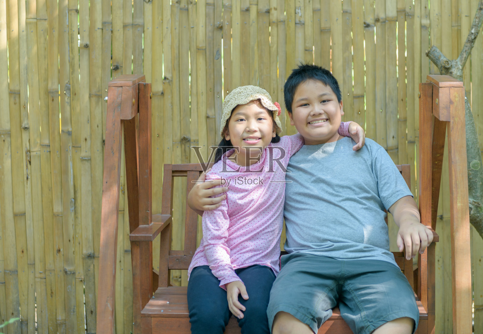 快乐的弟弟和妹妹微笑着坐在秋千上。照片摄影图片