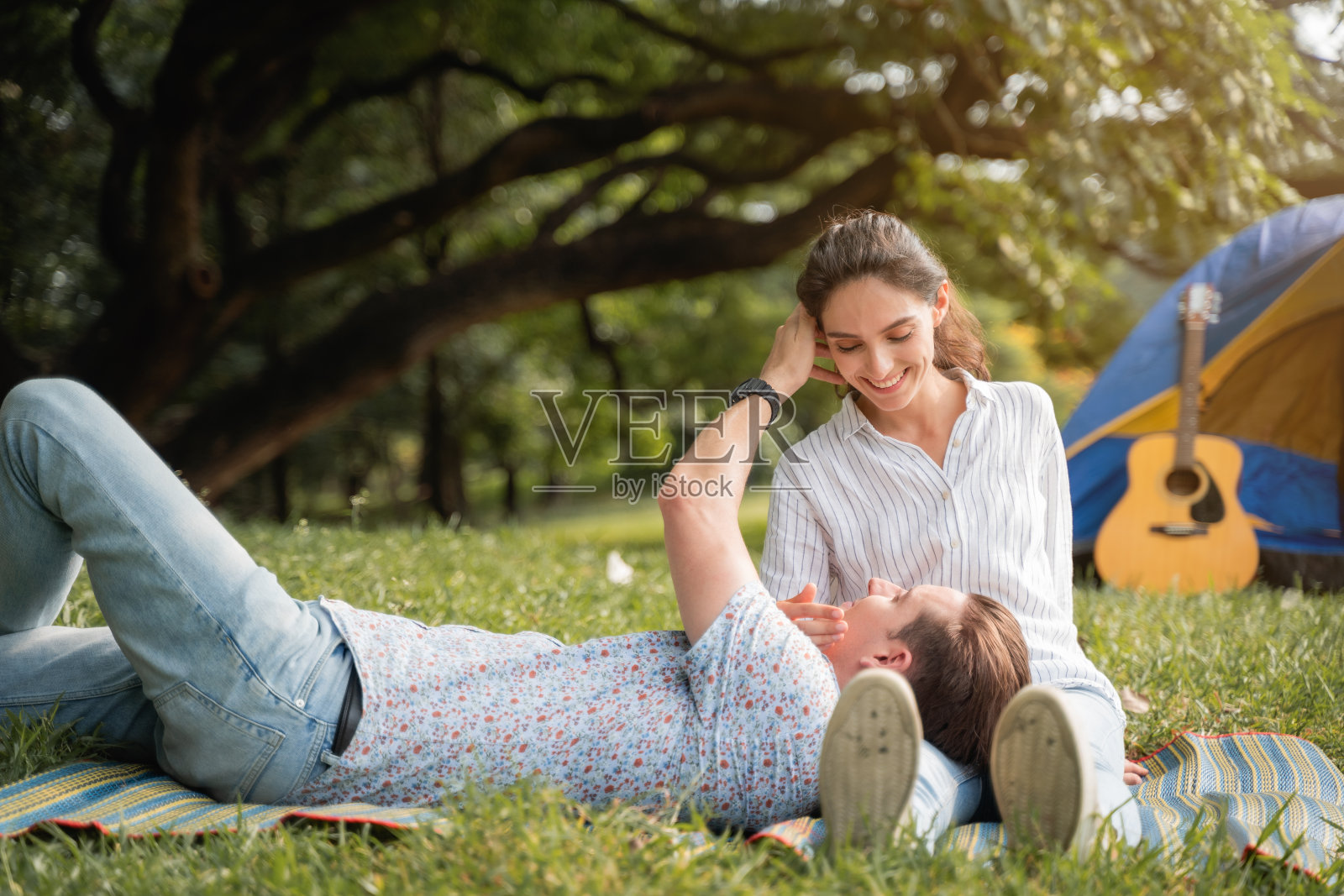 野餐和露营时间。年轻夫妇躺在草地上，充满浪漫的感觉。爱和温柔，浪漫的男人对他的女朋友微笑，生活理念照片摄影图片
