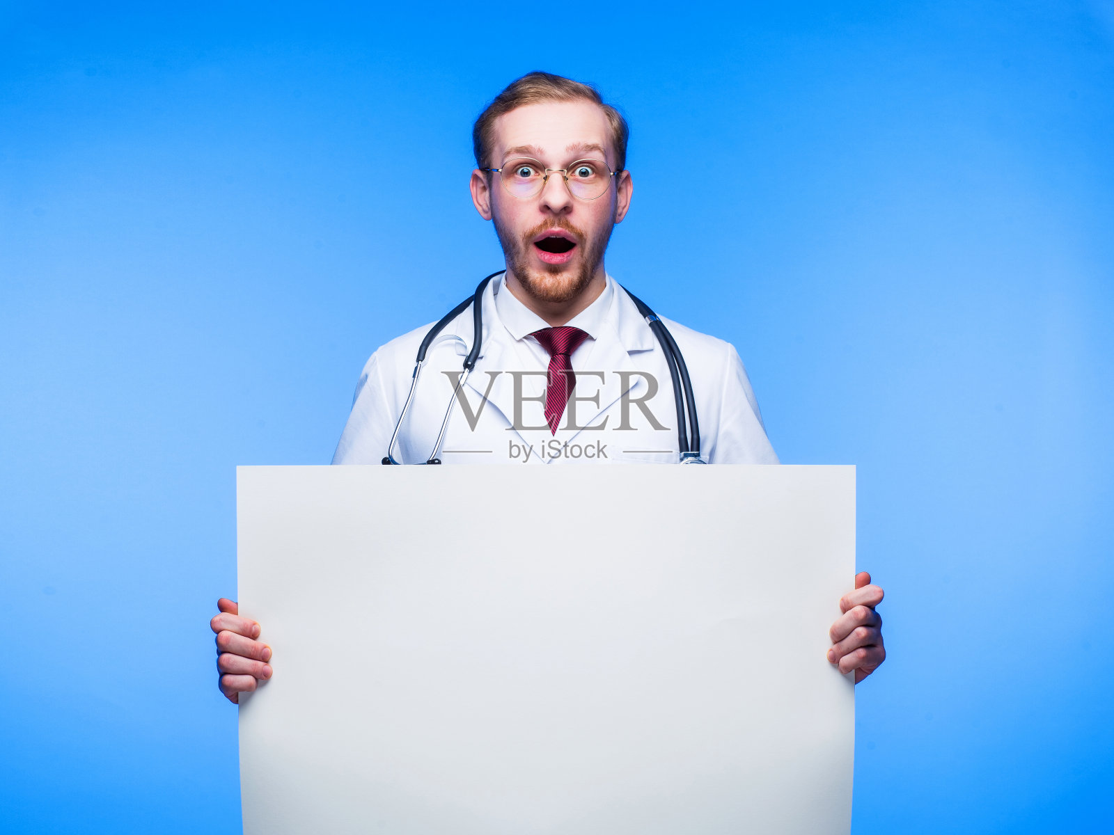 惊讶的医生手里拿着一张白纸。医学上紧急新闻和发现的概念。照片摄影图片
