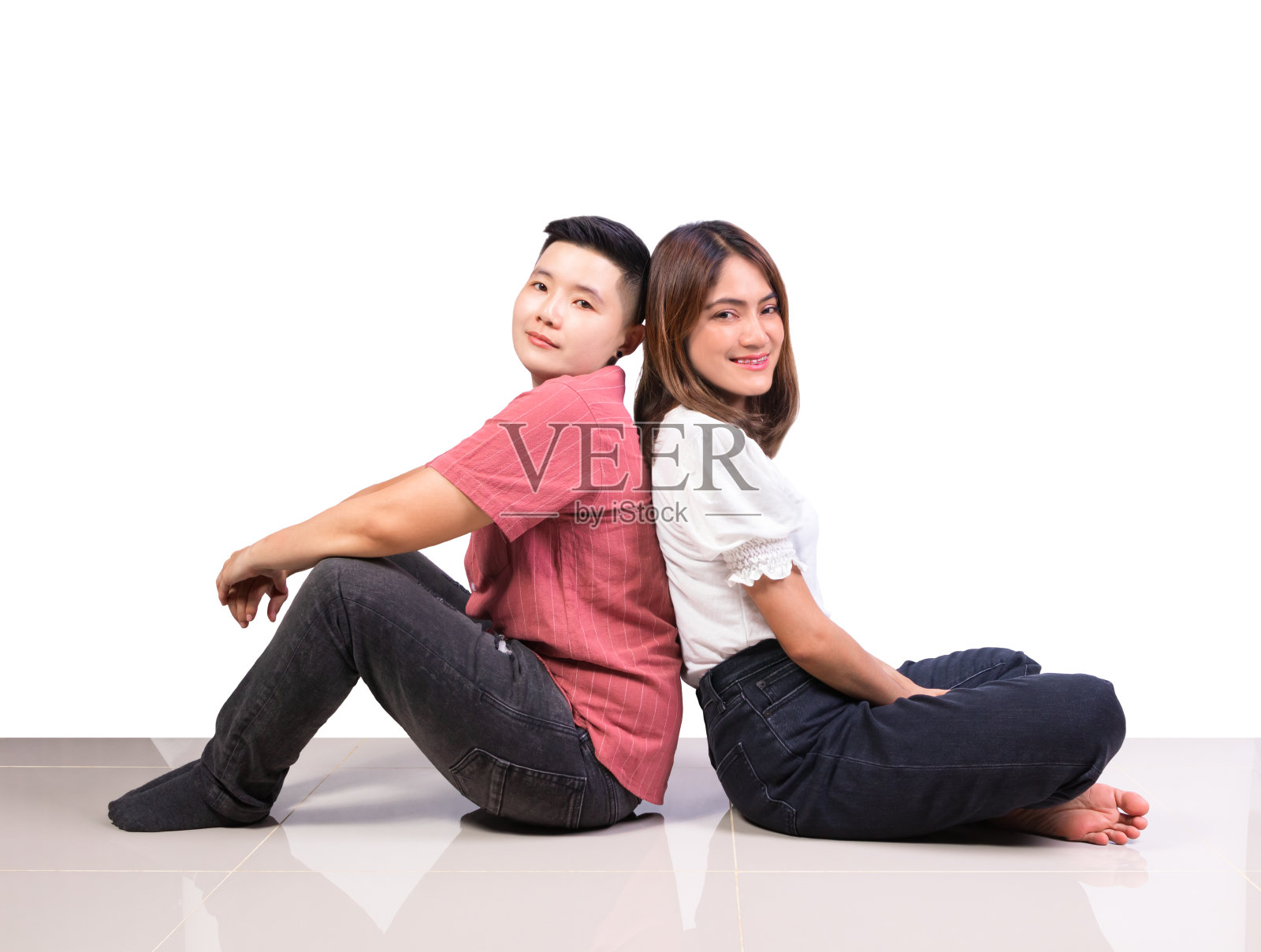 两个微笑的女人年轻的女孩和幸福的假小子朋友坐在瓷砖地板上背靠背在家里的白色背景照片摄影图片