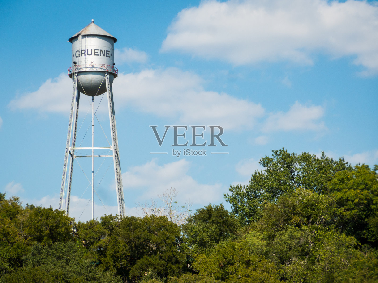 在阳光明媚的日子里，德州小镇格鲁恩的一个金属水箱高高耸立在树上照片摄影图片