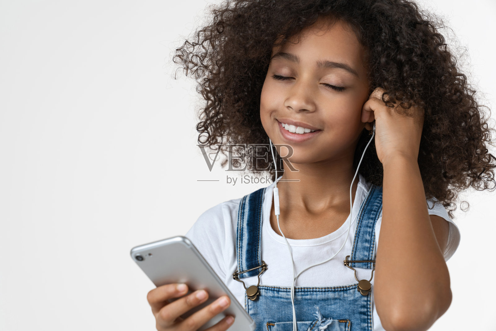 近距离的孩子听音乐和享受耳机在白色孤立的背景照片摄影图片