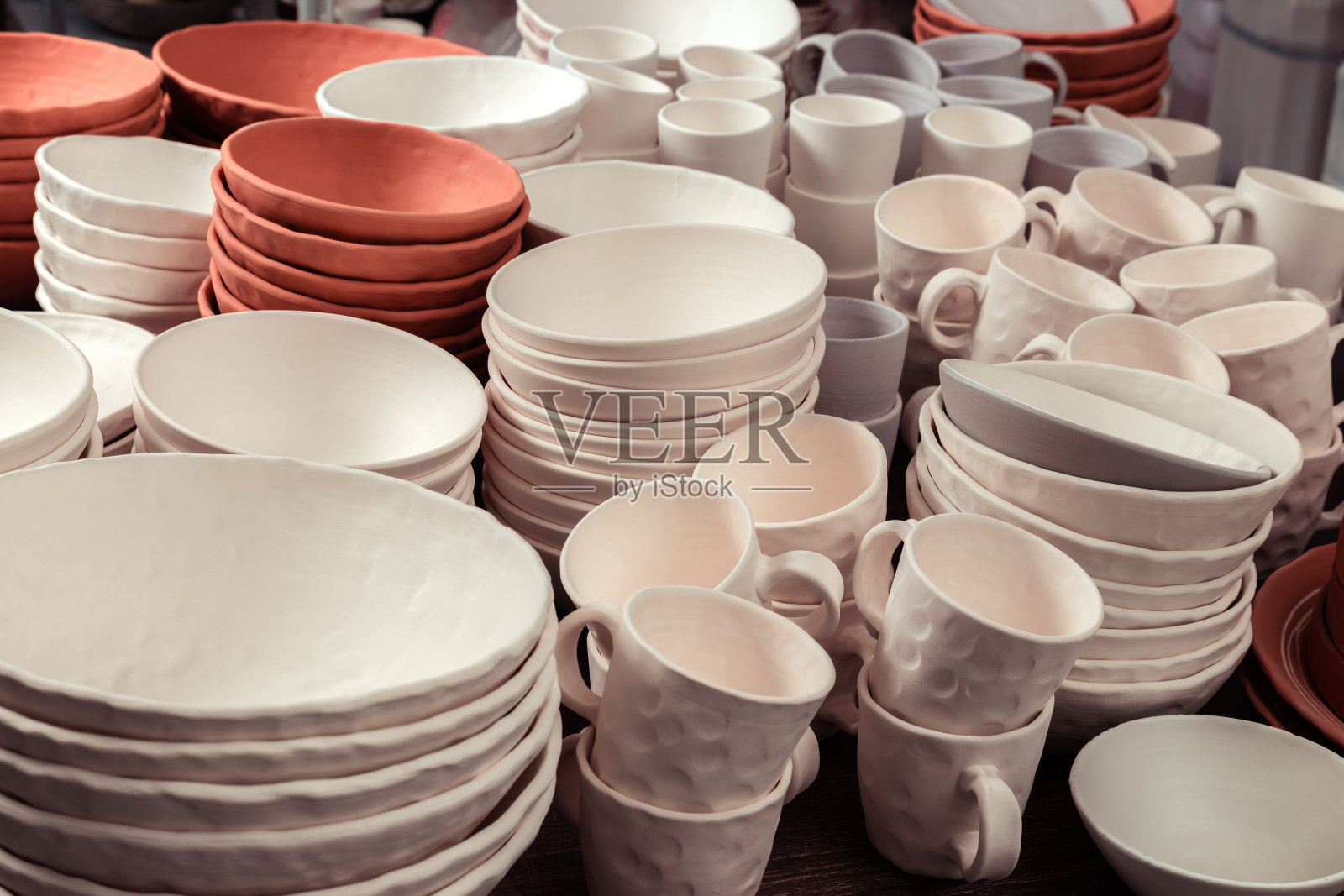 堆叠的陶瓷碗，盘子和杯子，陶土手工制品壶正在等待烘烤在陶工工作室的窑照片摄影图片