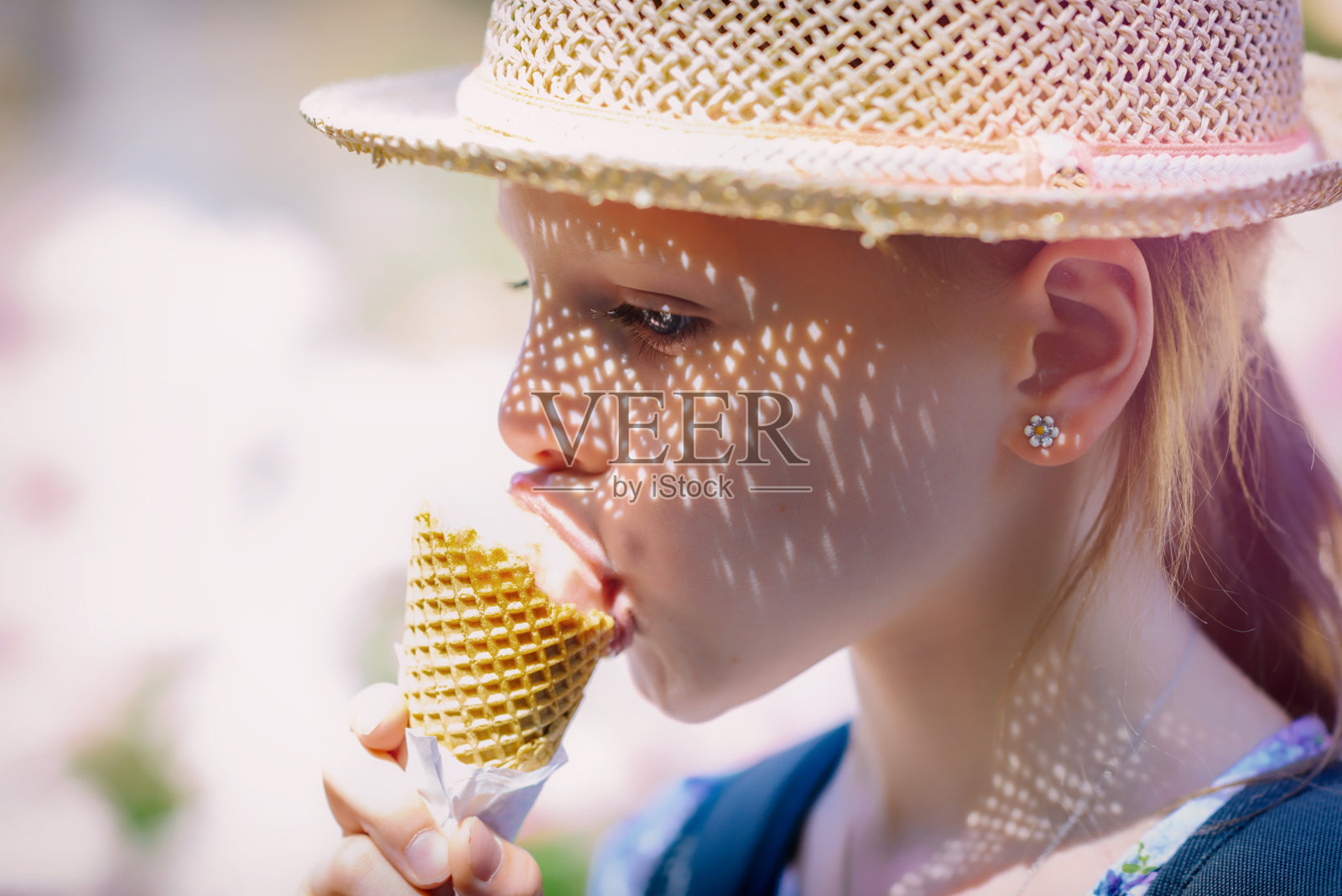 小女孩戴着草帽吃蛋筒冰淇淋照片摄影图片