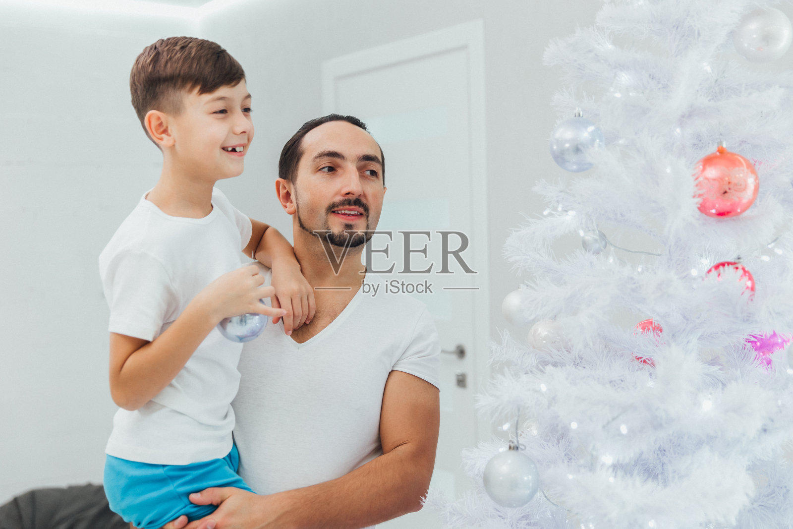 父子俩装饰圣诞树。圣诞节的家庭传统照片摄影图片