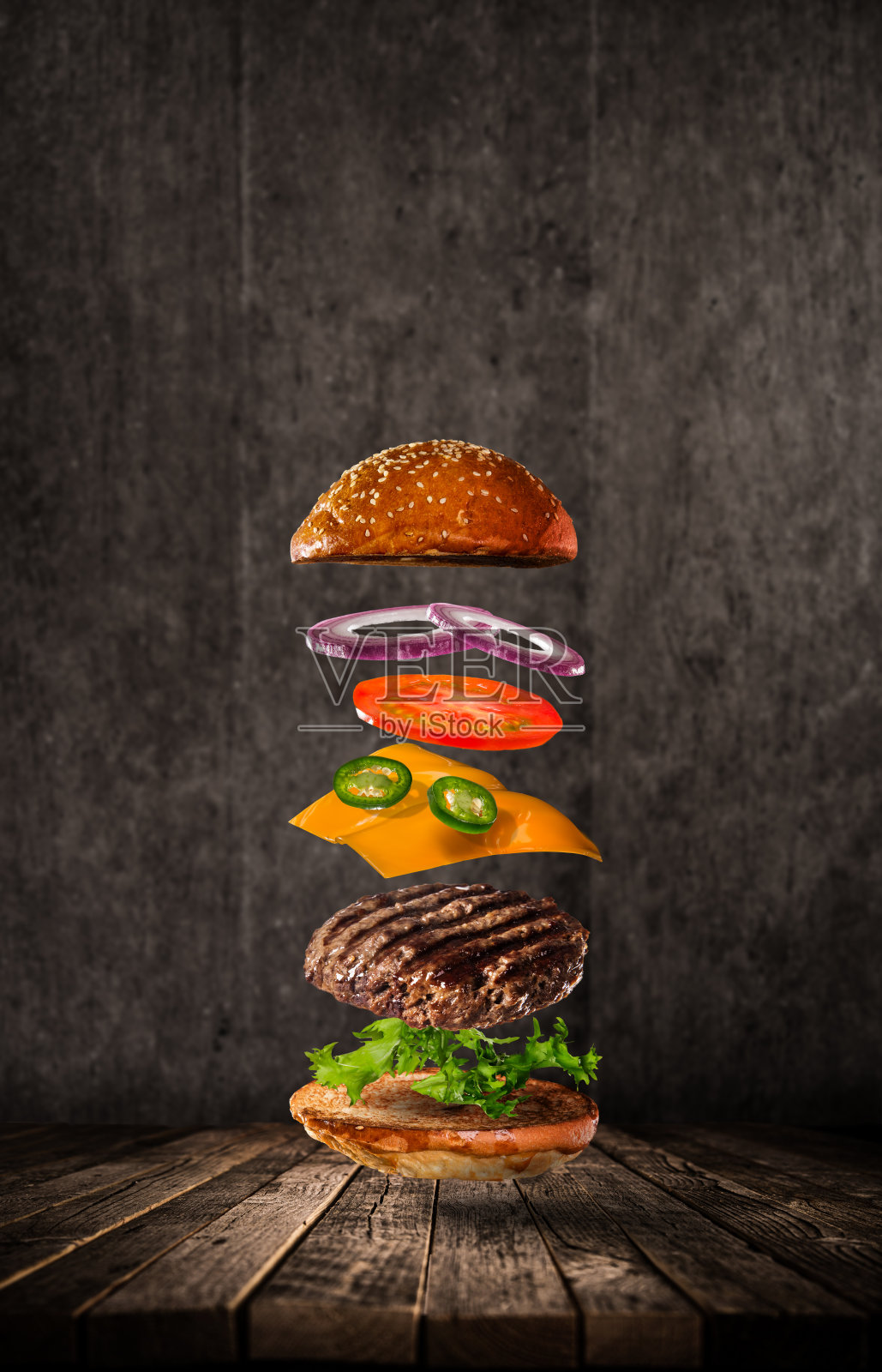 美味的汉堡与飞行的原料在黑暗的背景照片摄影图片