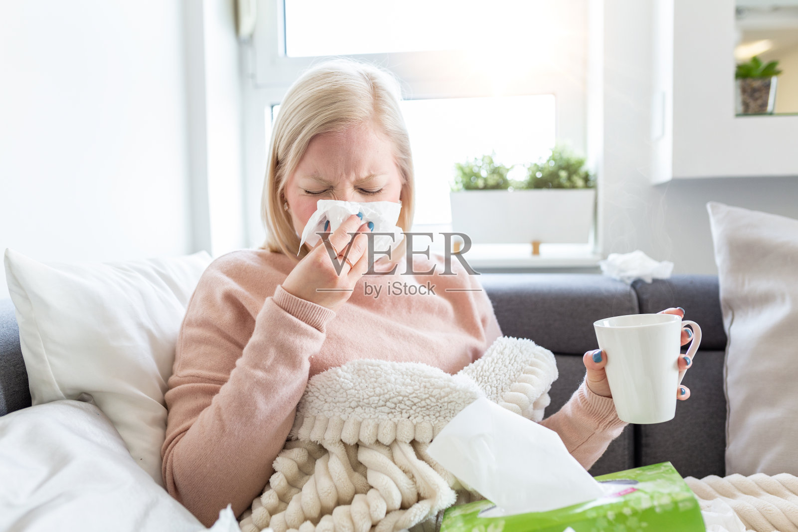 感冒和流感。生病的女人的肖像感冒，生病和打喷嚏在纸擦。用毯子擦鼻子的不健康女孩。医疗保健的概念。白化女孩病了，喝热饮照片摄影图片