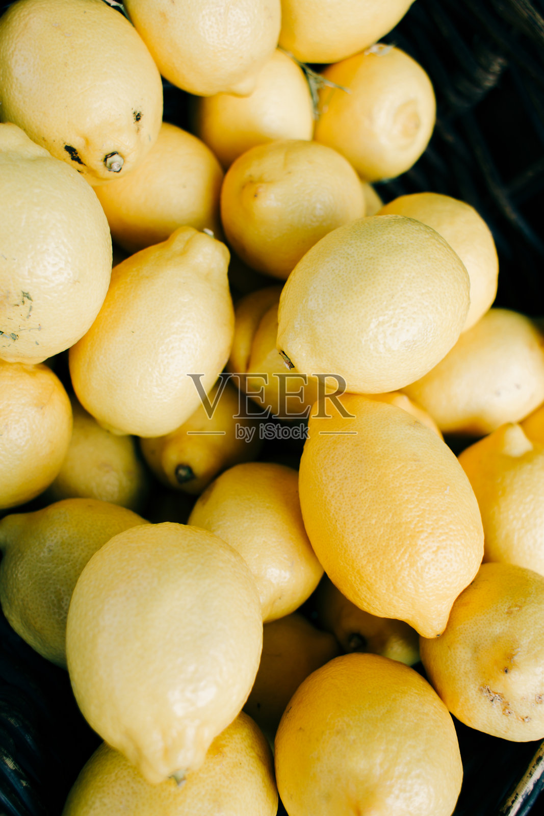 在有机市场，成熟的黄柠檬躺在一个柳条篮子里照片摄影图片
