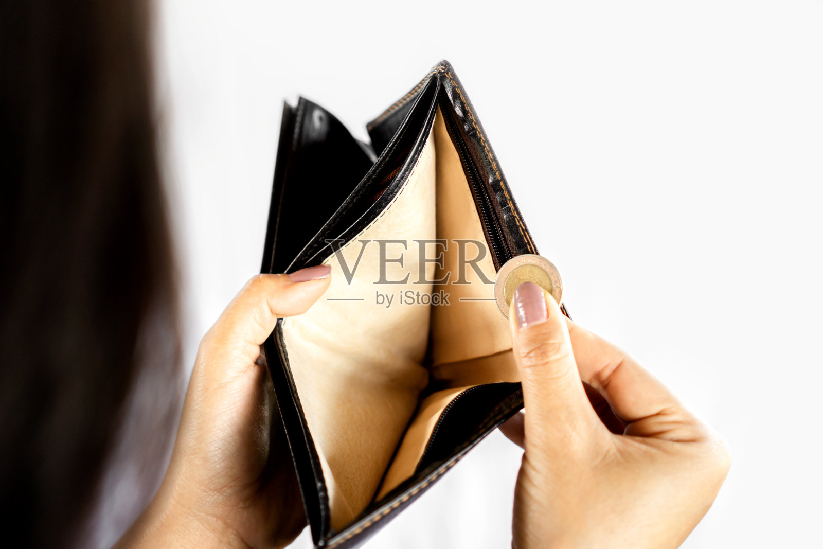 可怜的女人一手打开空钱包，另一只手里只拿着一枚硬币，发薪日和破产的概念照片摄影图片