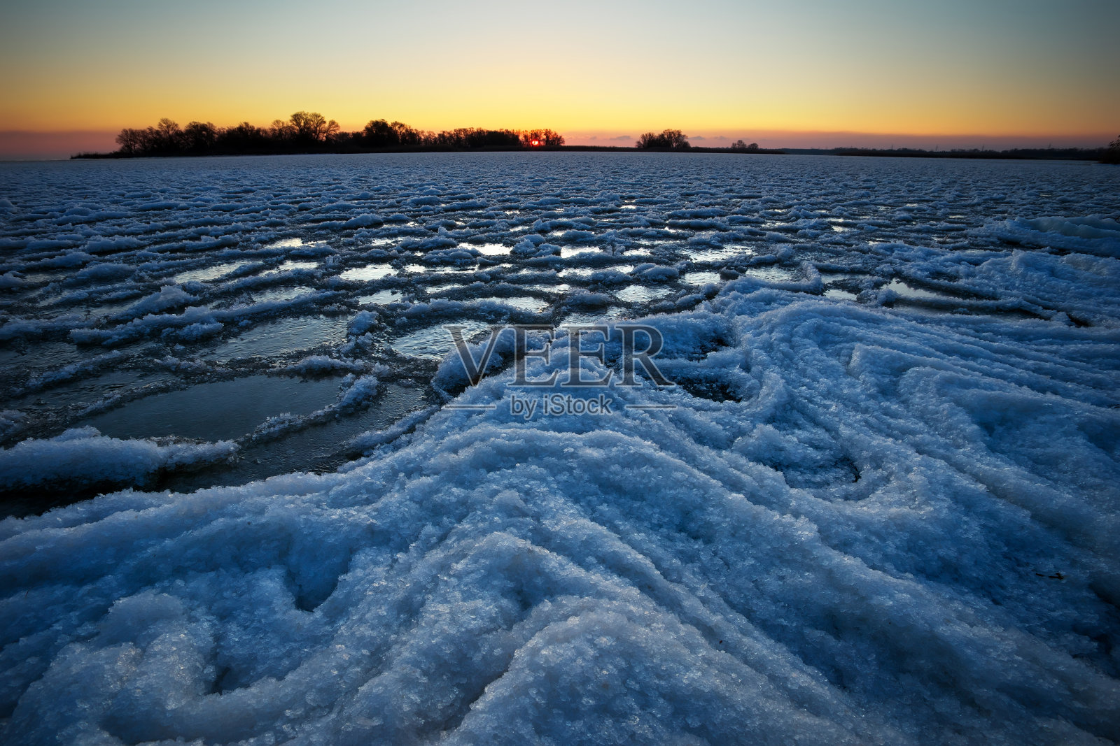 日出和冰冻的河流。美丽的冬季景观与湖泊在早晨的时间。黎明照片摄影图片