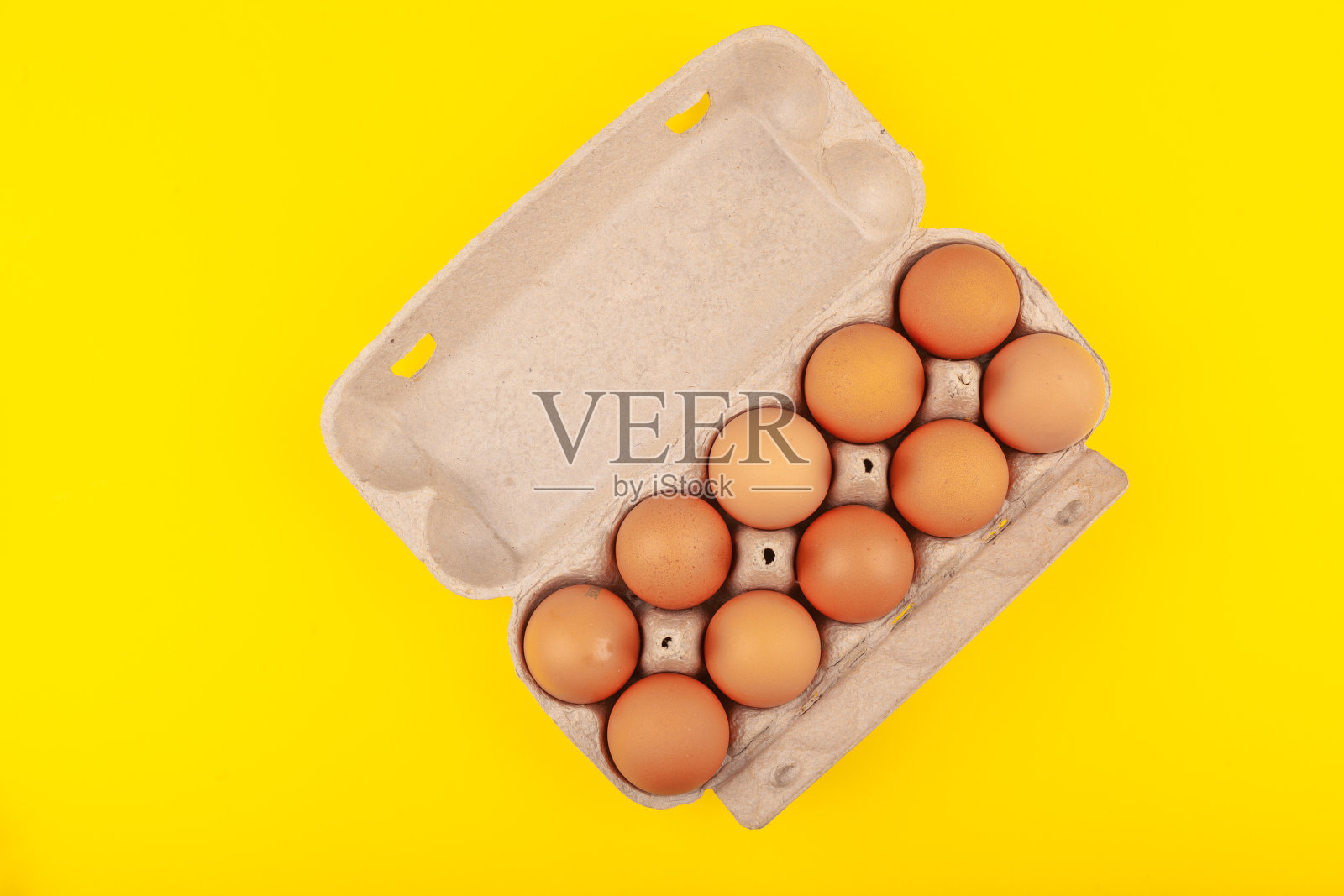 鸡蛋鸡蛋。一个打开的灰色盒子的俯视图，棕色的鸡蛋孤立在黄色的背景。健康生活方式的概念，获得纯蛋白质。适当的早餐照片摄影图片