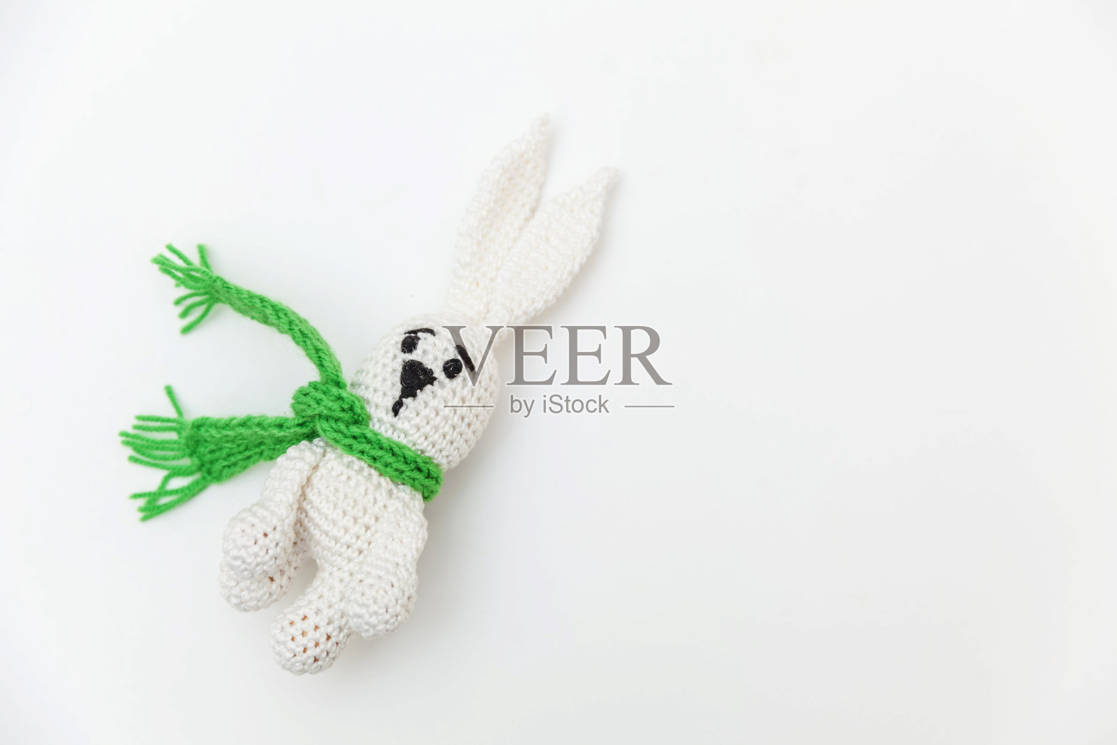 简单的最小设计与玩具兔子在绿色围巾孤立的白色背景。儿童关爱母性家庭理念。平铺，俯视图，拷贝空间照片摄影图片