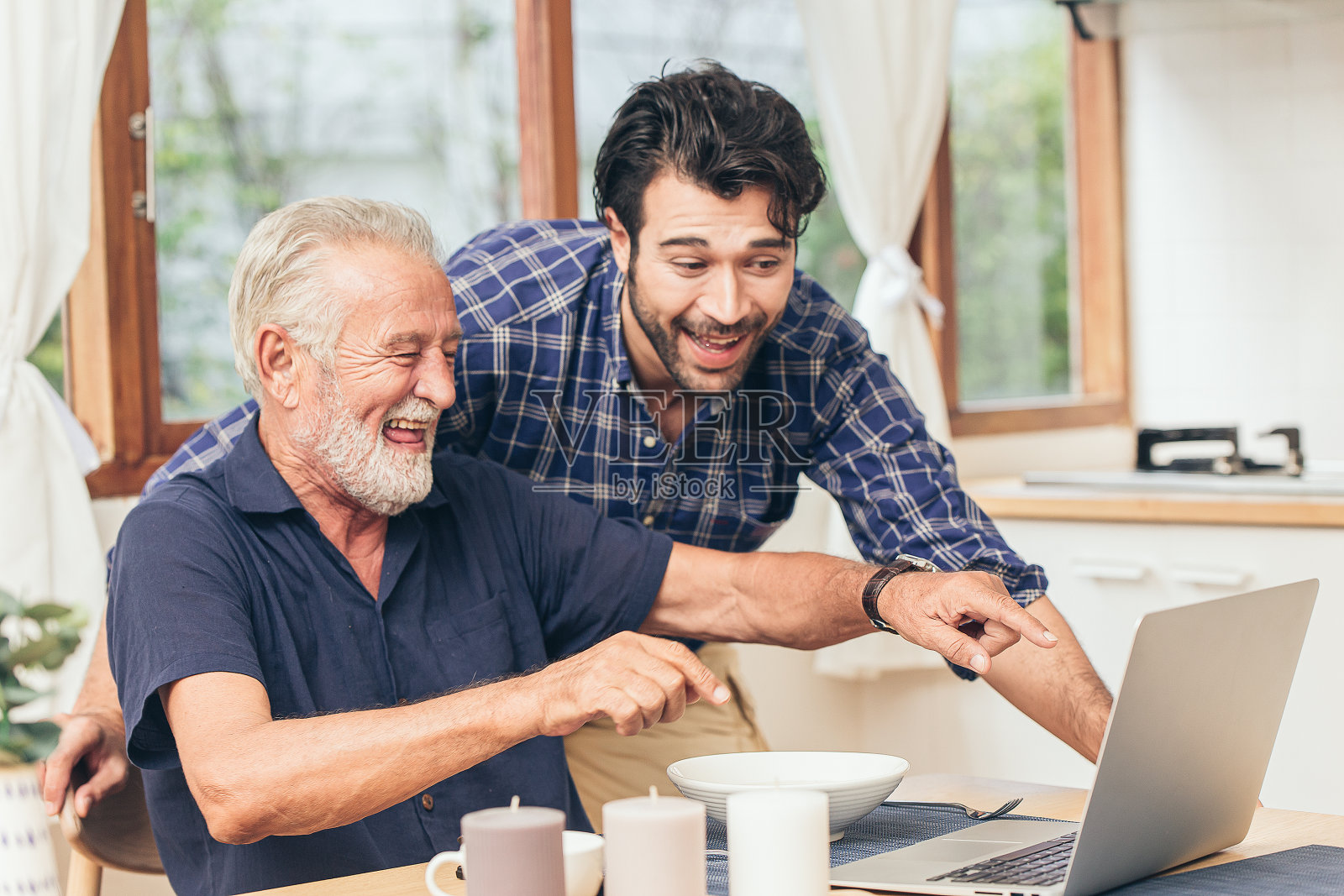 老人开心地笑着和儿子一起看笔记本电脑。用通讯技术为家庭幸福、养老、居家养老联系其他理念照片摄影图片