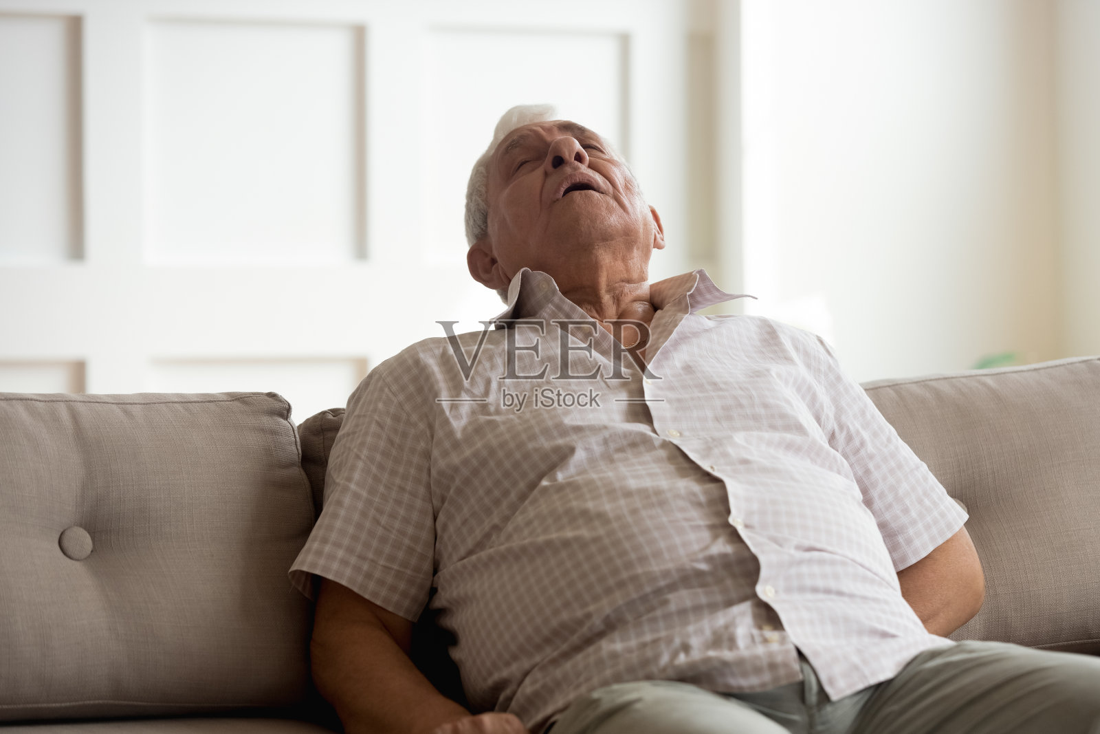 精疲力竭的老人在家里的沙发上睡着了照片摄影图片