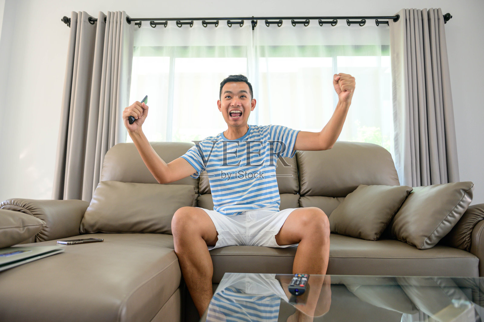 男人在电视上看足球，在家庆祝胜利，体育和娱乐的概念。照片摄影图片