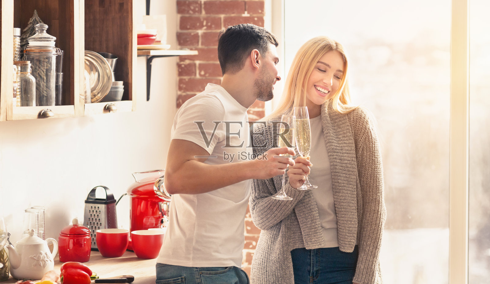 年轻夫妇在厨房里微笑着喝着香槟照片摄影图片