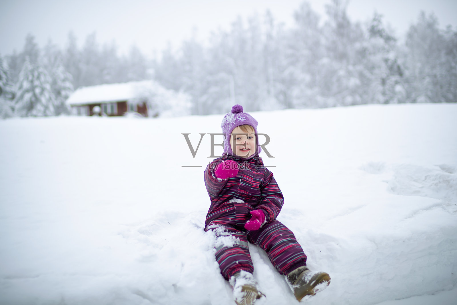 一个小女孩正坐在雪地上照片摄影图片