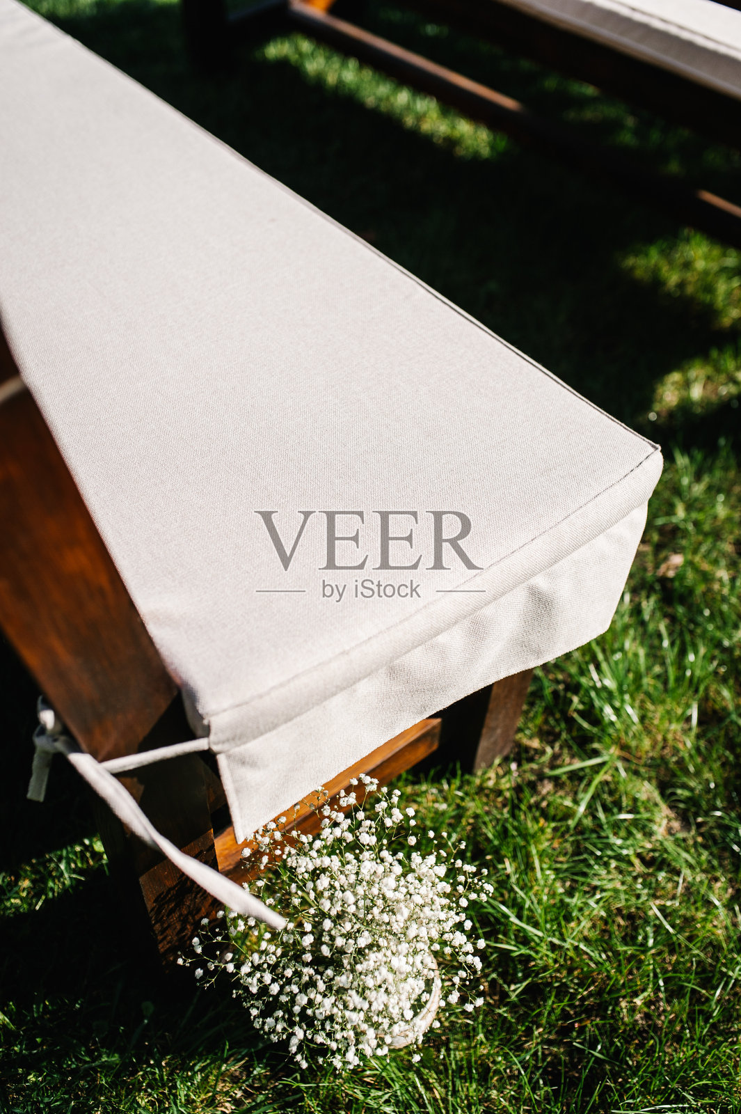 装饰着花的棕色椅子。绿色的草坪上有棕色的木凳。婚礼仪式。户外的概念。照片摄影图片