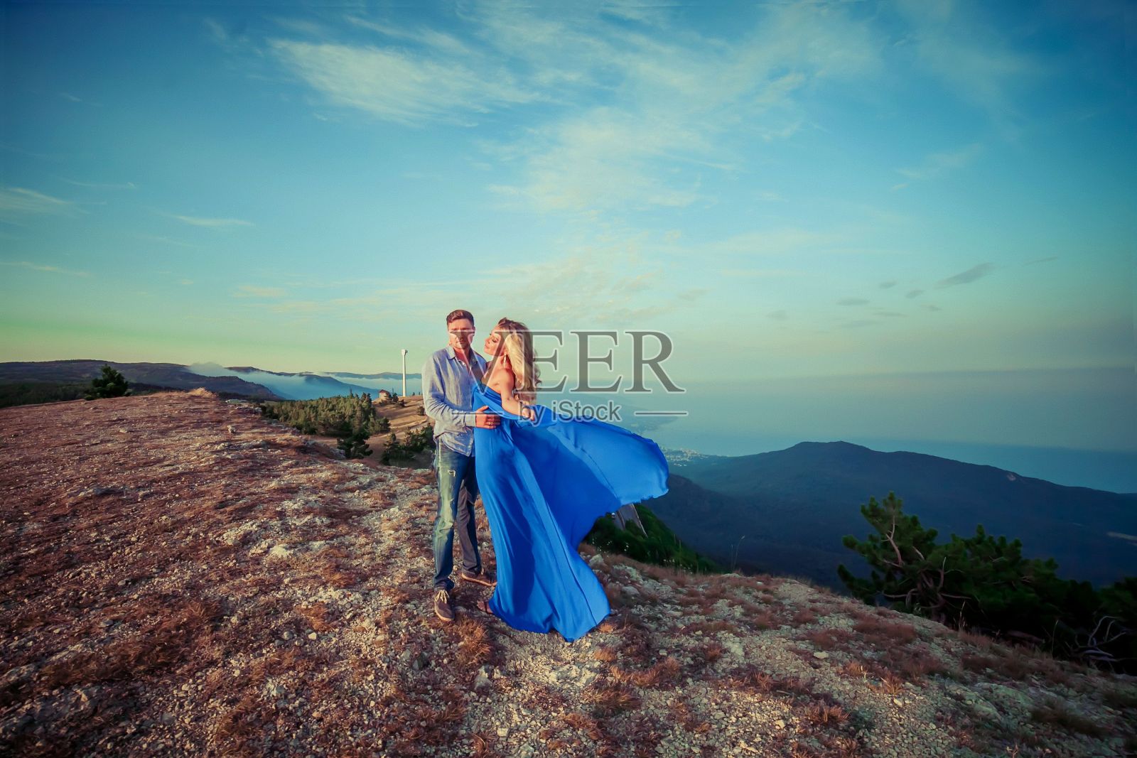 一对年轻的新婚夫妇站在山顶上拥抱照片摄影图片
