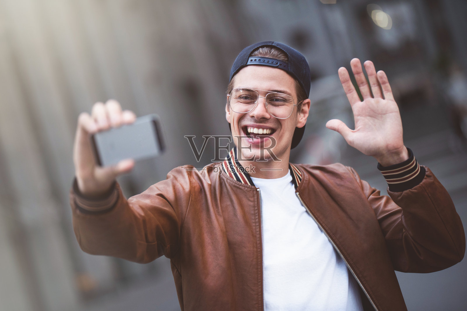 英俊快乐的年轻白人男子在街上用相机自拍的照片。照片摄影图片
