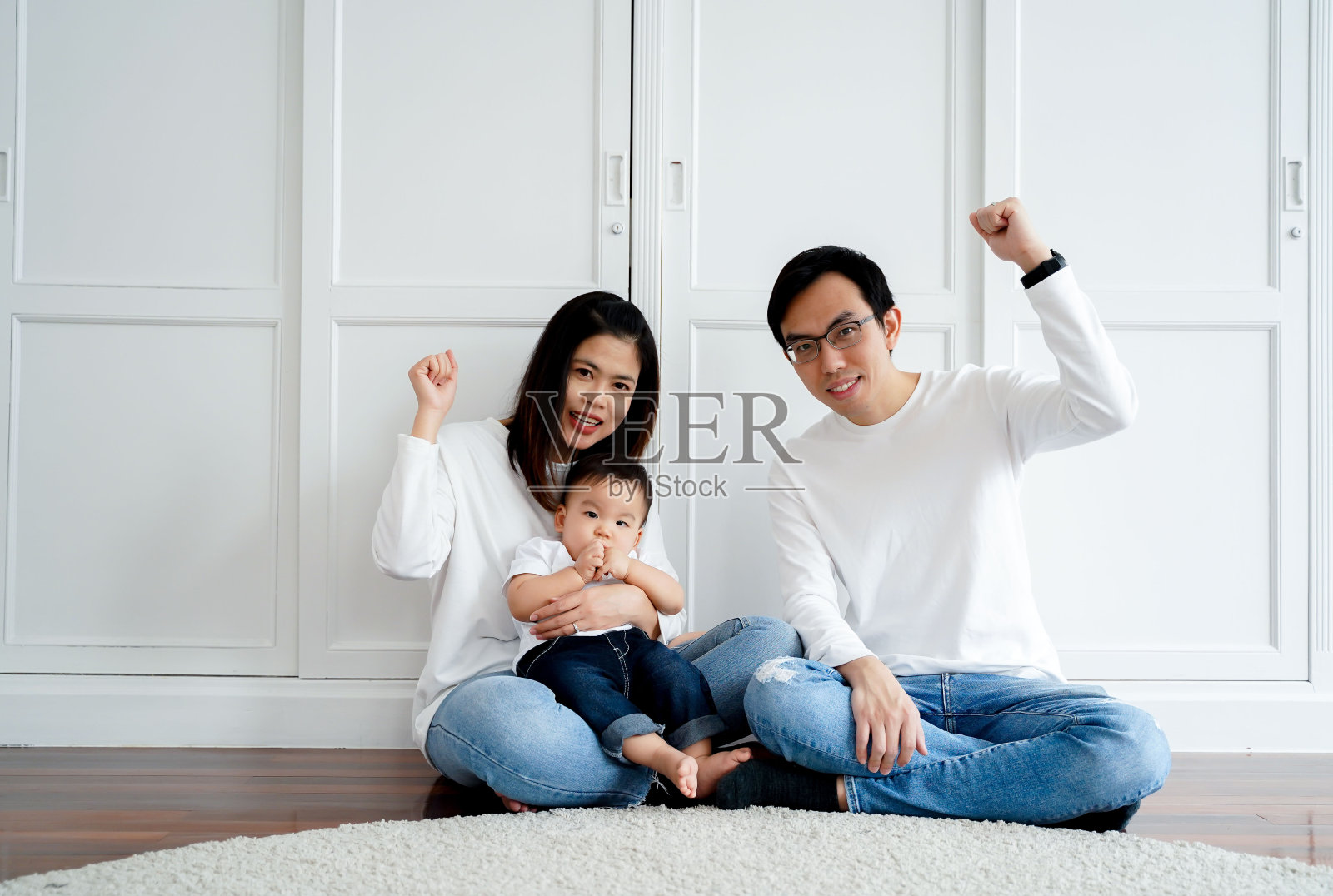 乐观的亚洲父亲，母亲和儿子作为家庭举起手来，为成功在家里全长。亚洲的亲子观念照片摄影图片