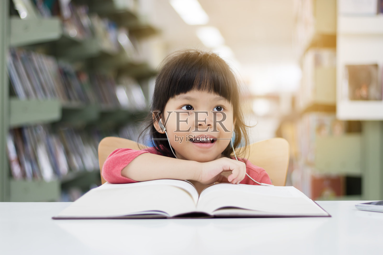 亚洲女孩在图书馆里愉快地看书和听音乐。照片摄影图片