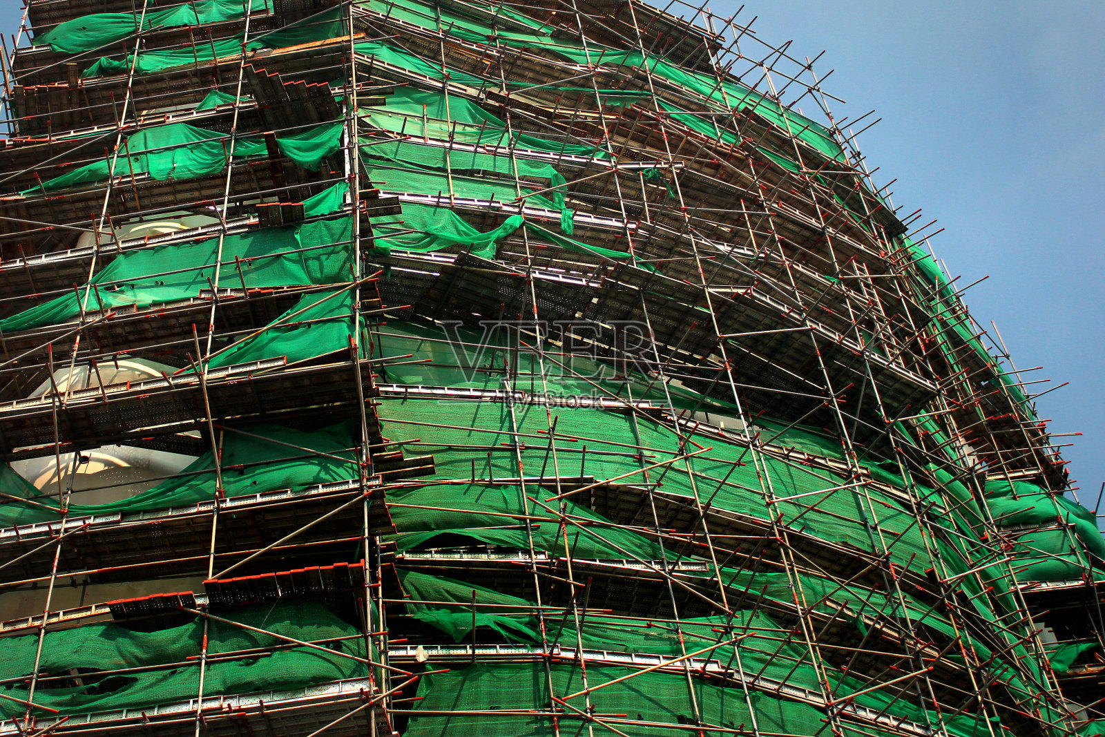 建筑工地的脚手架，外立面覆盖着绿色网格照片摄影图片