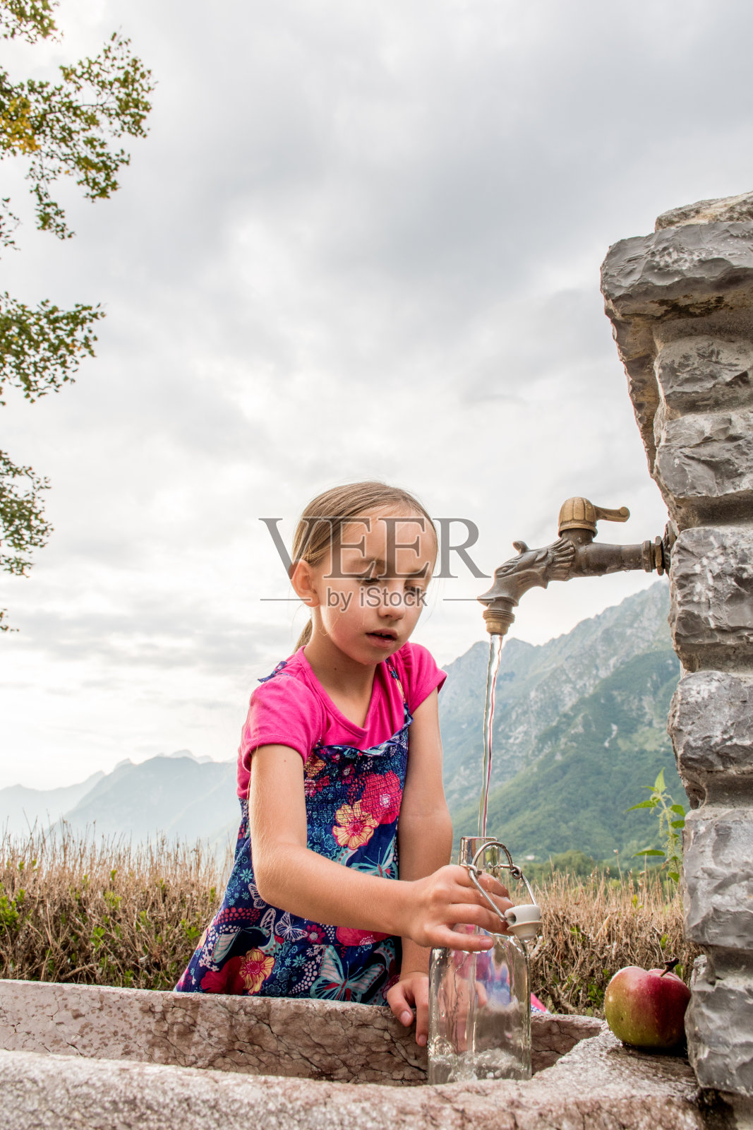 女孩在山村的水龙头里装水照片摄影图片