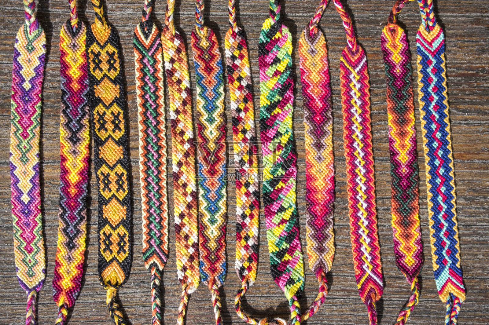 一组简单手工自制的友谊天然编织手链，以木制为背景，彩虹色，格子图案照片摄影图片