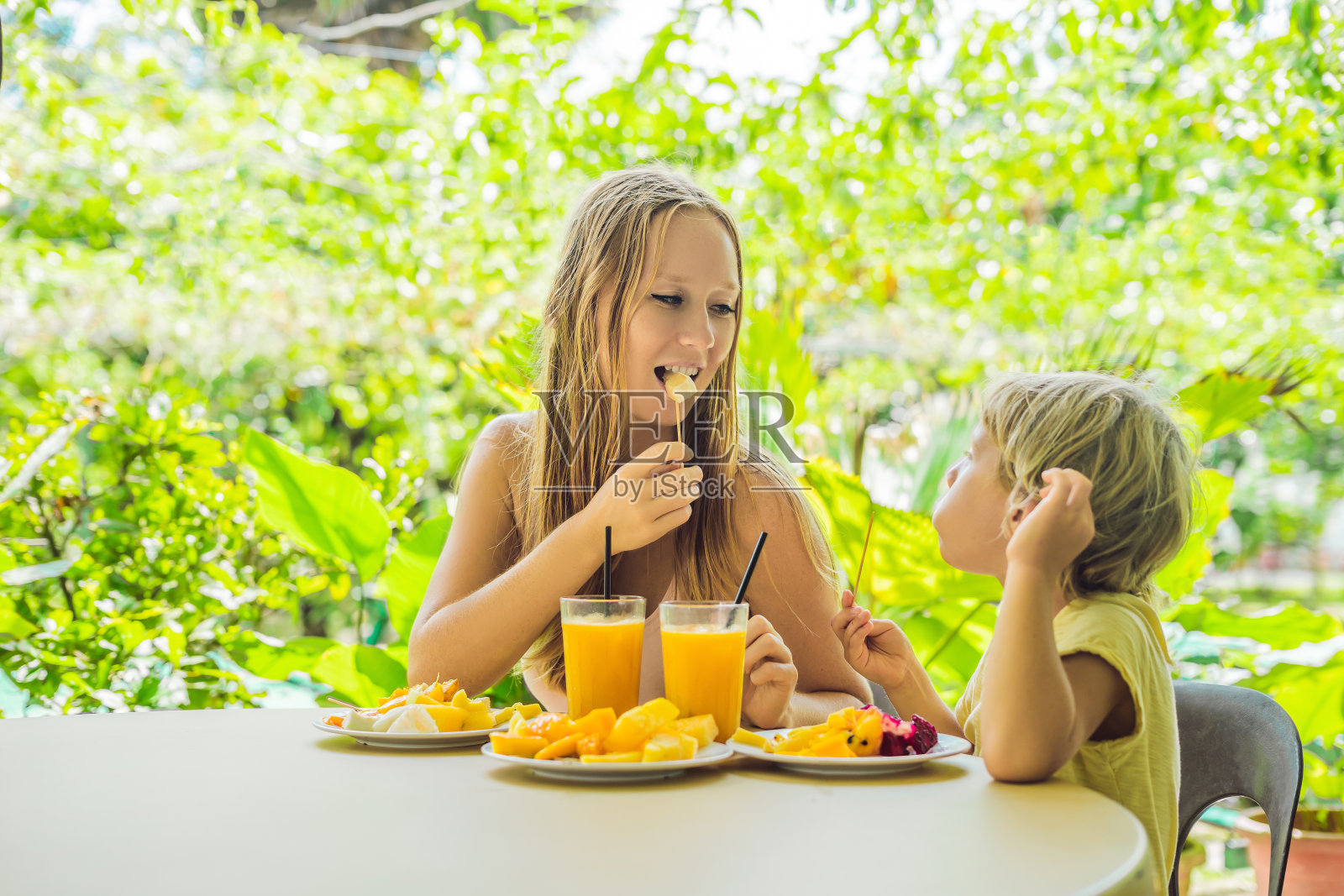 妈妈和儿子在咖啡馆里吃水果和果汁照片摄影图片