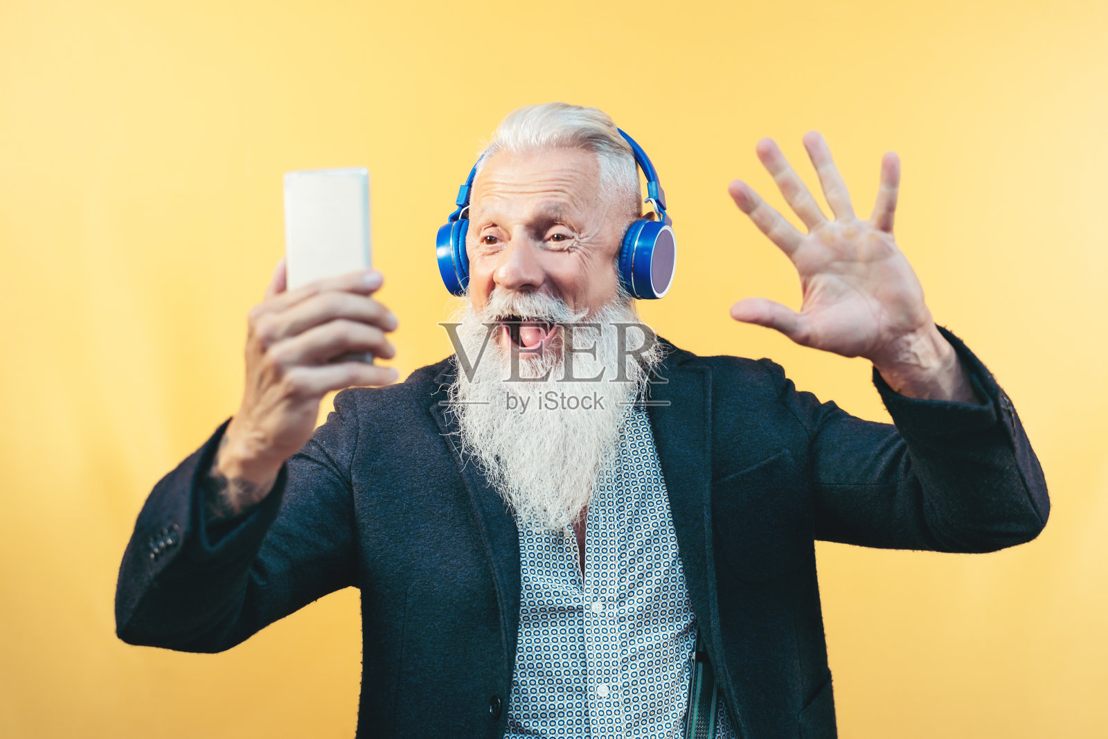 快乐的老年人边听音乐边自拍-留着时髦胡子的男性用手机播放列表的应用程序玩得很开心-技术和老年人的生活方式概念照片摄影图片