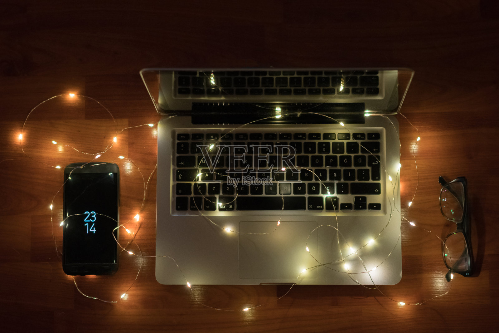 木制桌子上放着圣诞灯的笔记本电脑和智能手机照片摄影图片