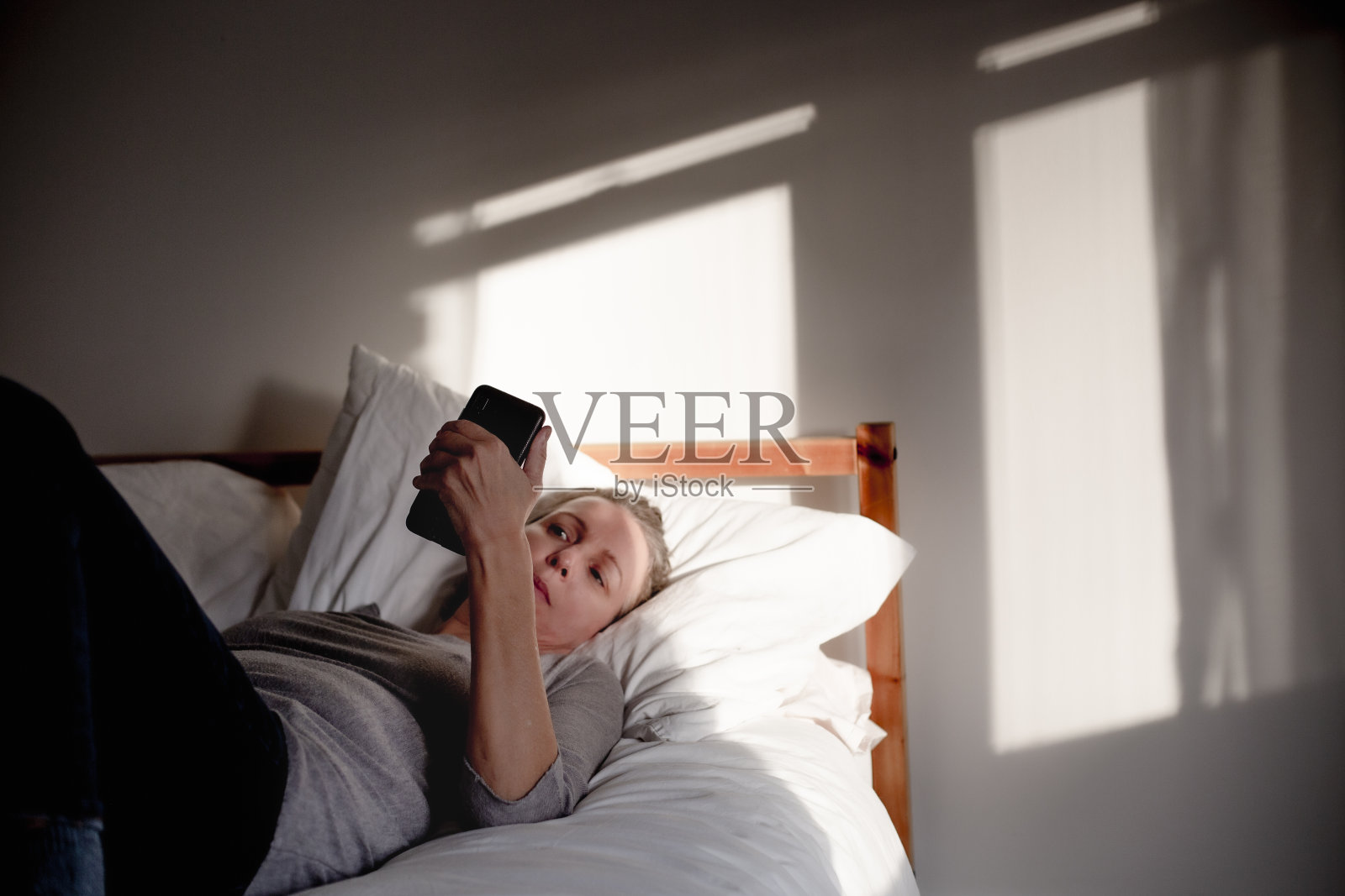 成熟的女人在床上拿着手机照片摄影图片
