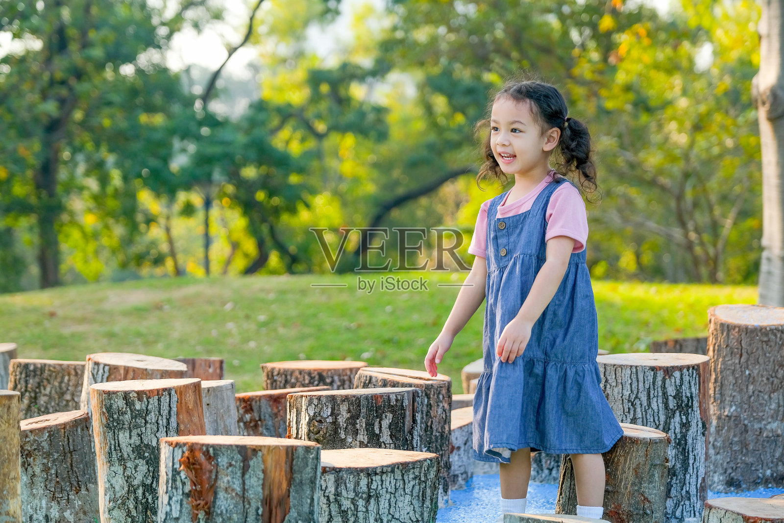 肖像的小亚洲女孩微笑和散步周围的木材在公园或花园照片摄影图片