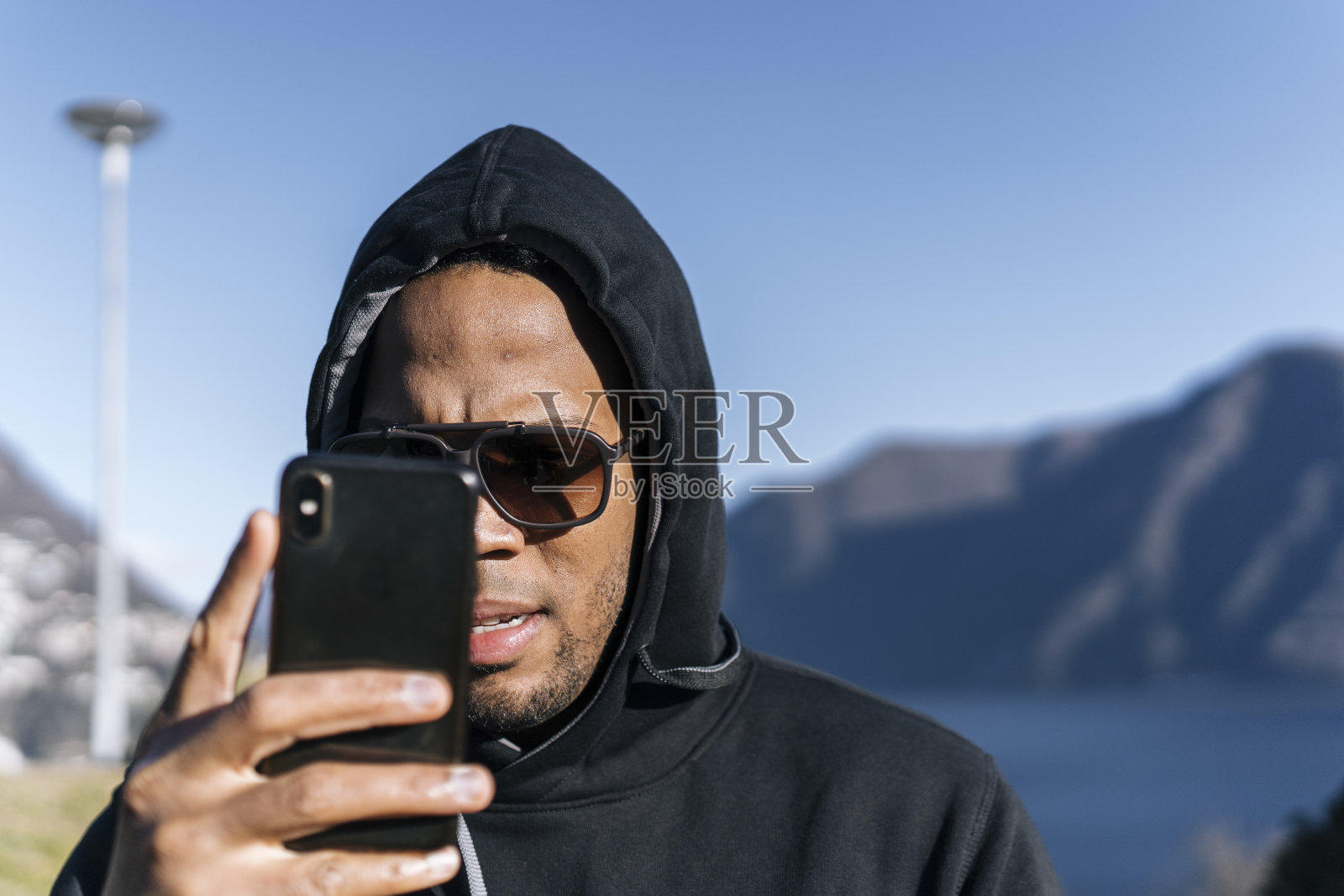 运动员用智能手机拍照，身后是山景湖照片摄影图片