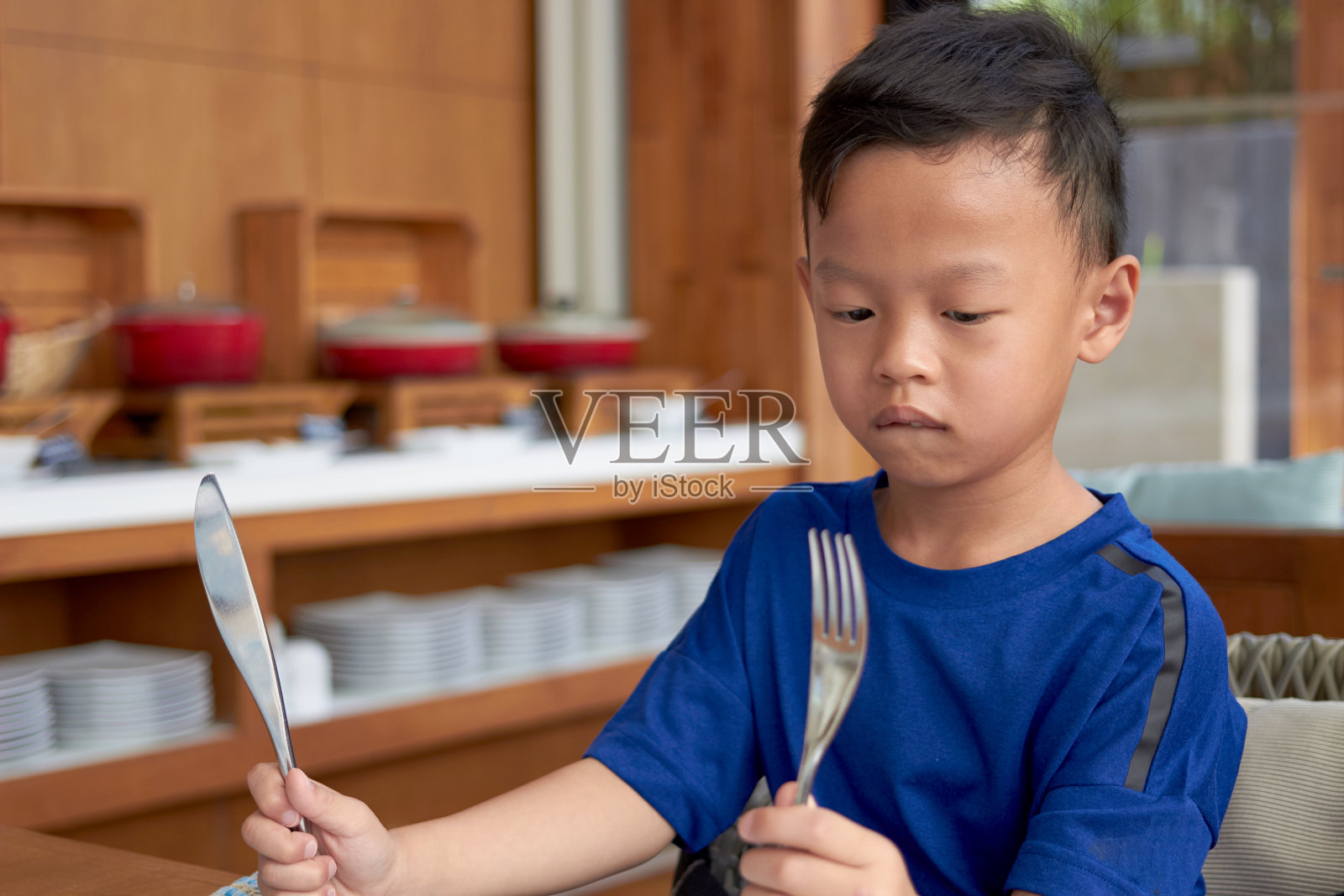 亚洲男孩拿着刀叉准备在餐桌上吃自助餐的背景照片摄影图片