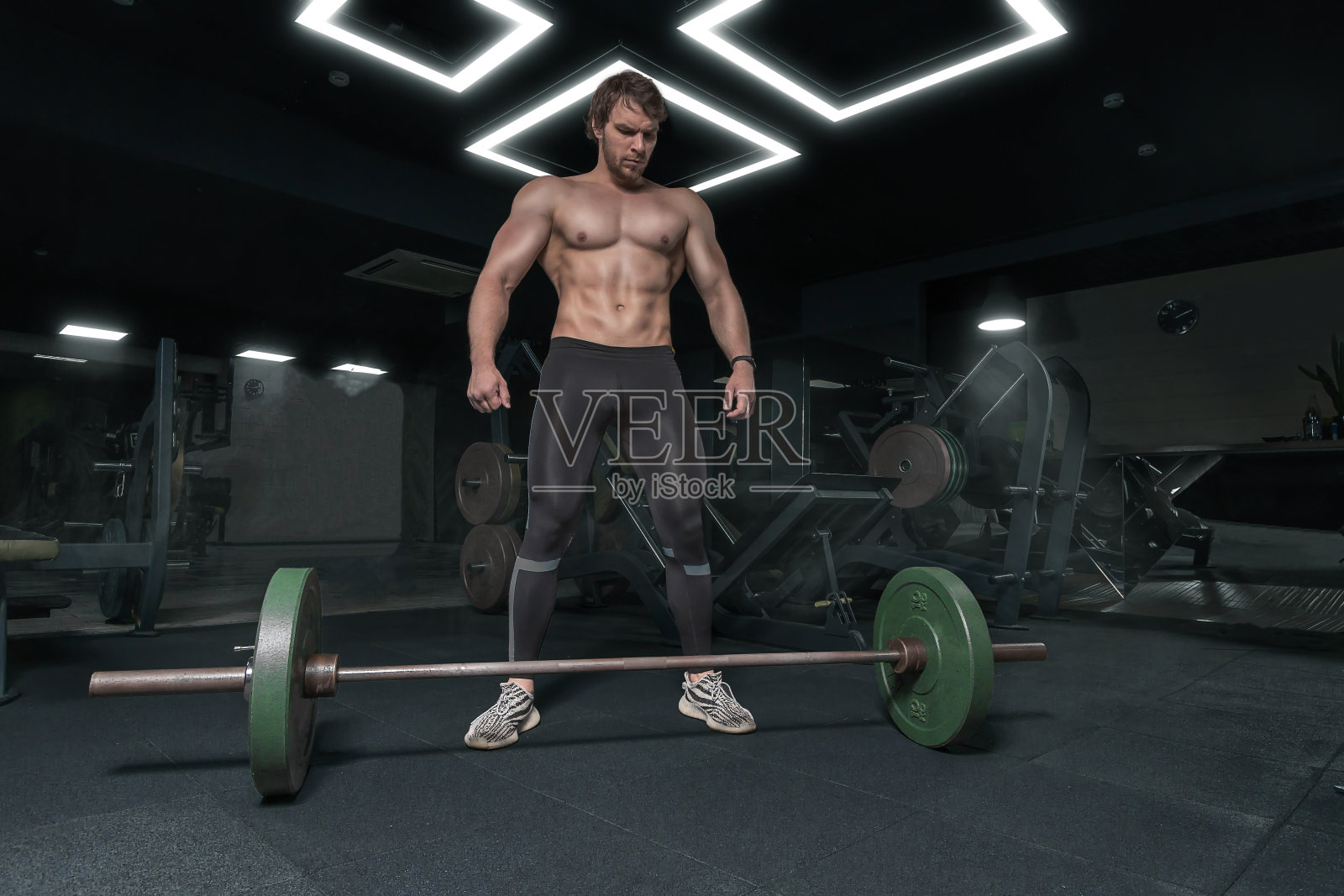 肌肉发达的强壮的运动员不看杠铃，在健身房锻炼照片摄影图片