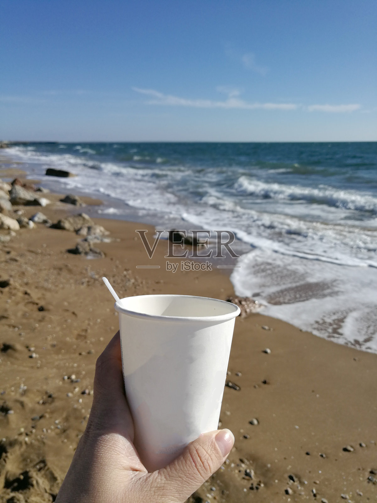 男人的手捧着一杯咖啡对着大海照片摄影图片